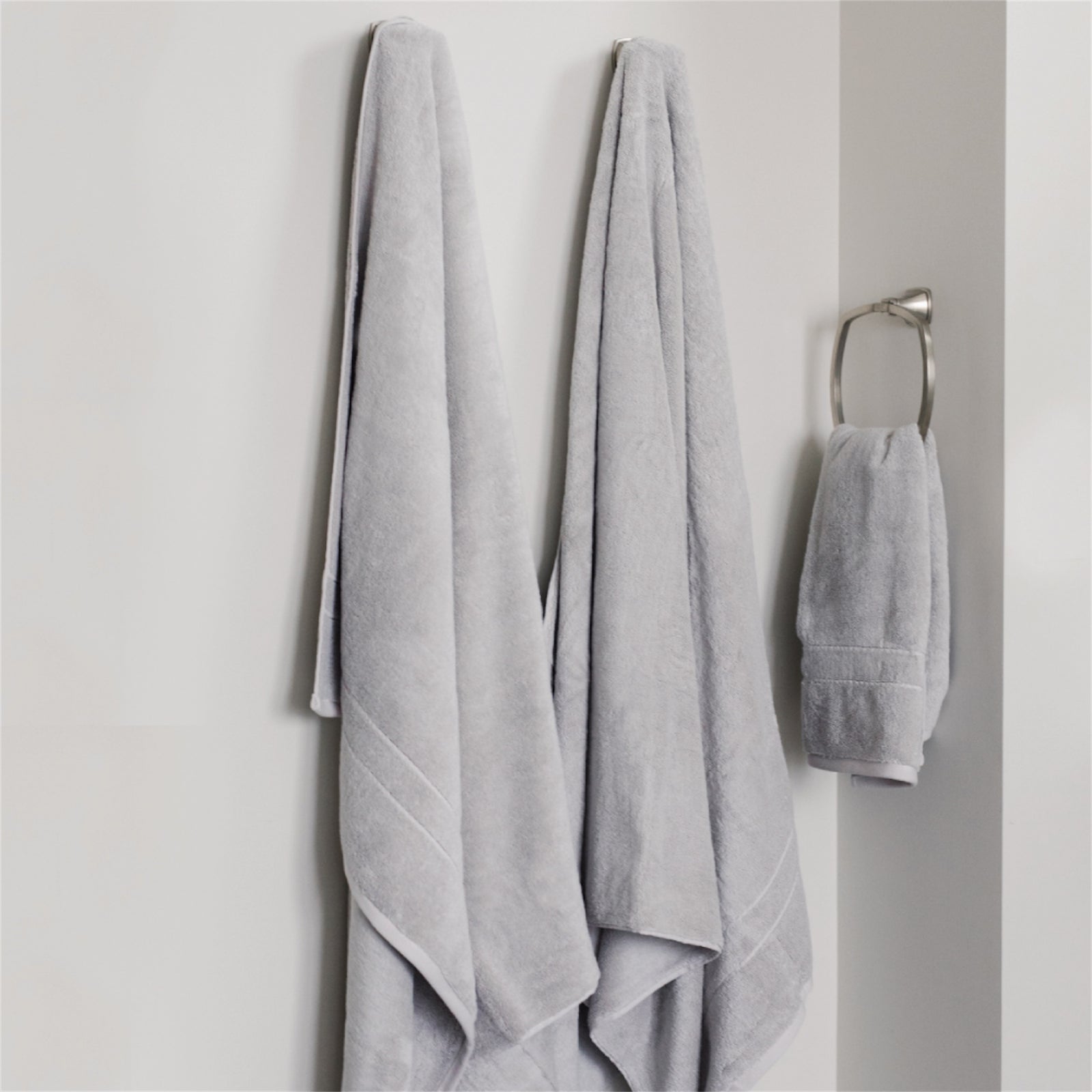 Premium Plush Bath Towels in the color Light Grey. Photo of Premium Plush Bath Towels taken in a bathroom showing the towels which are hung from a towel rack.