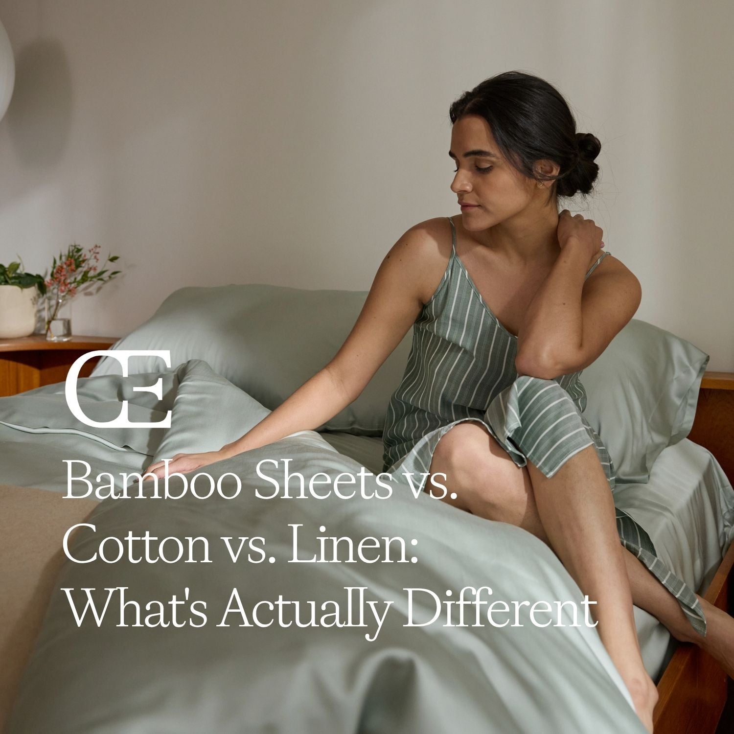 a woman sits in bed with light green sheets