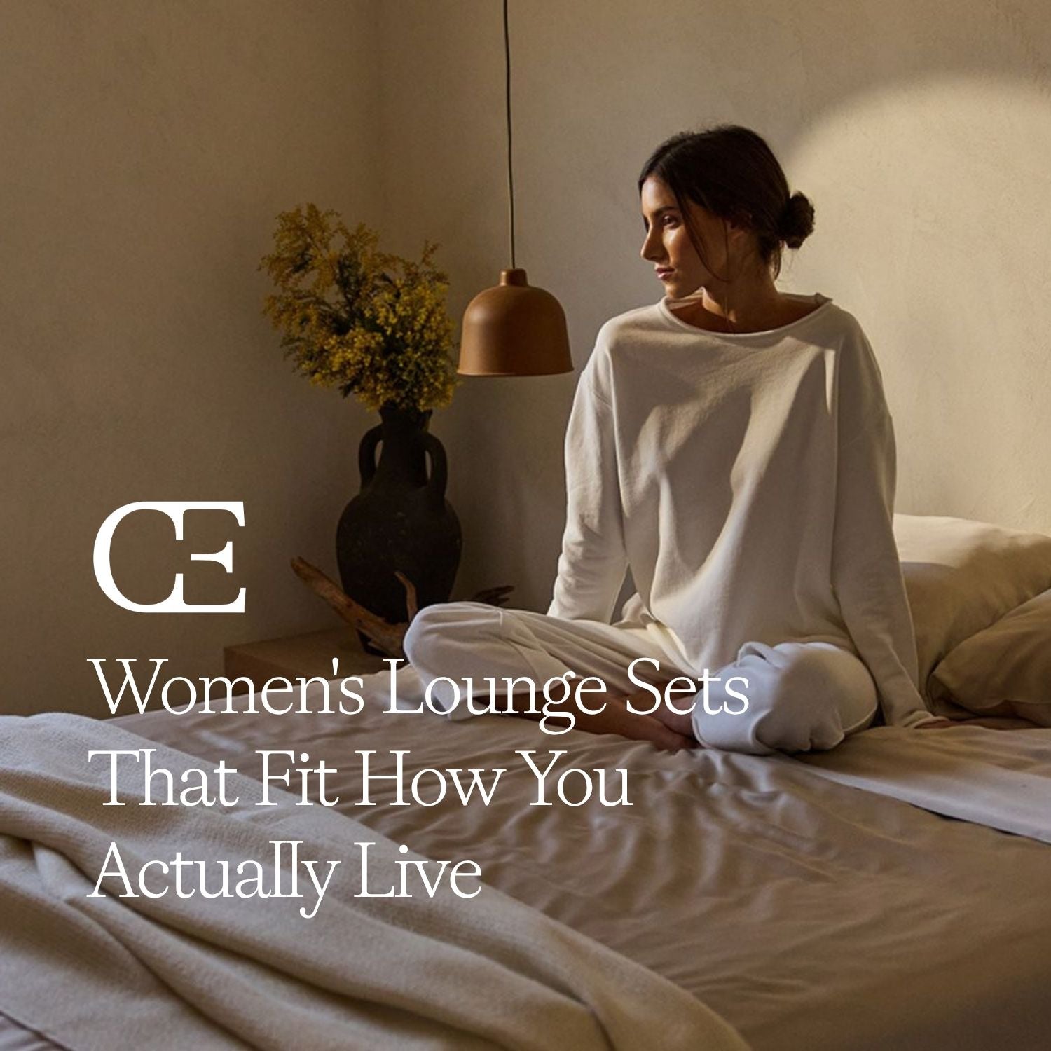 a woman sits on a bed wearing a white lounge set