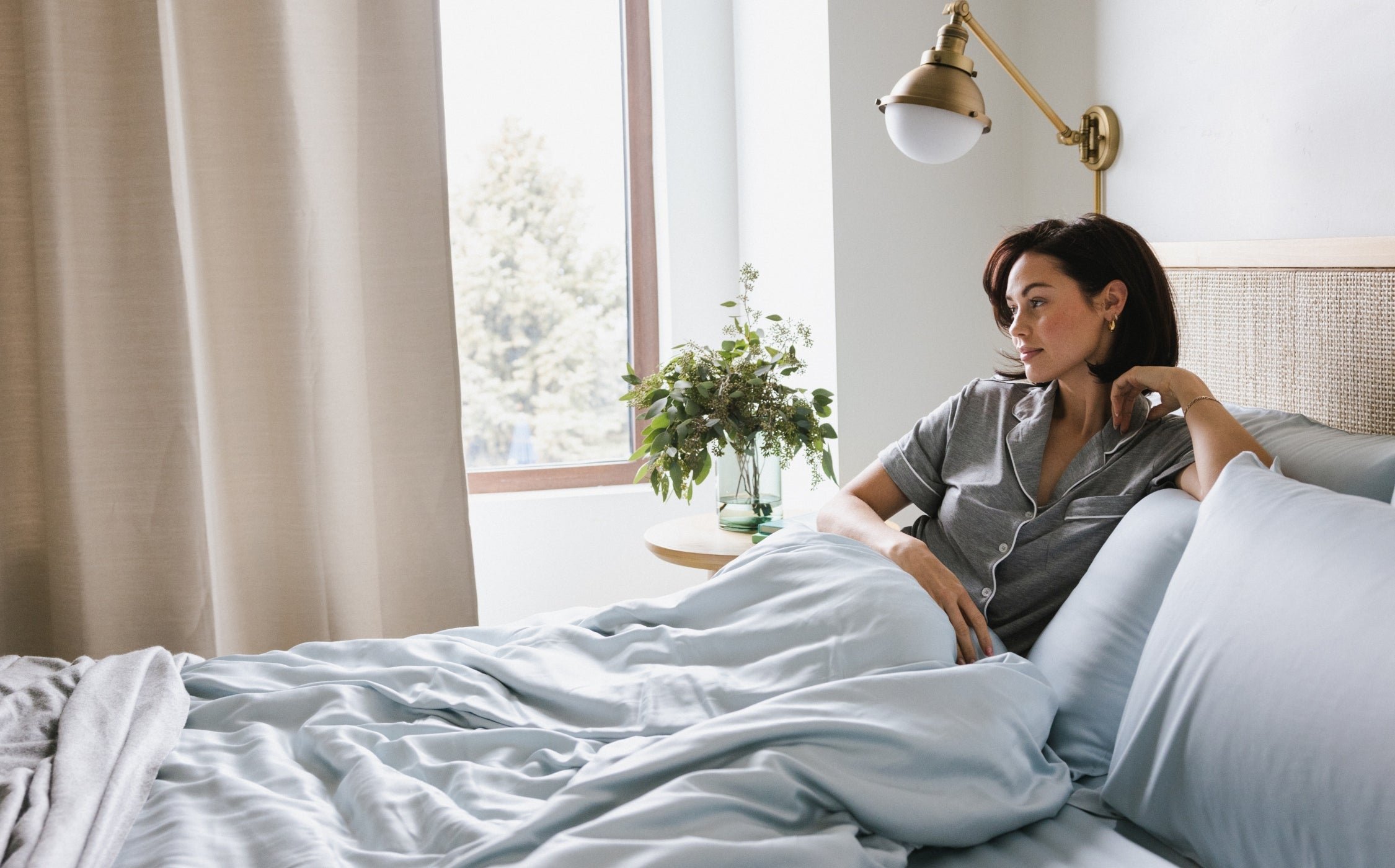 Women in short sleeve grey pajamas laying in bed