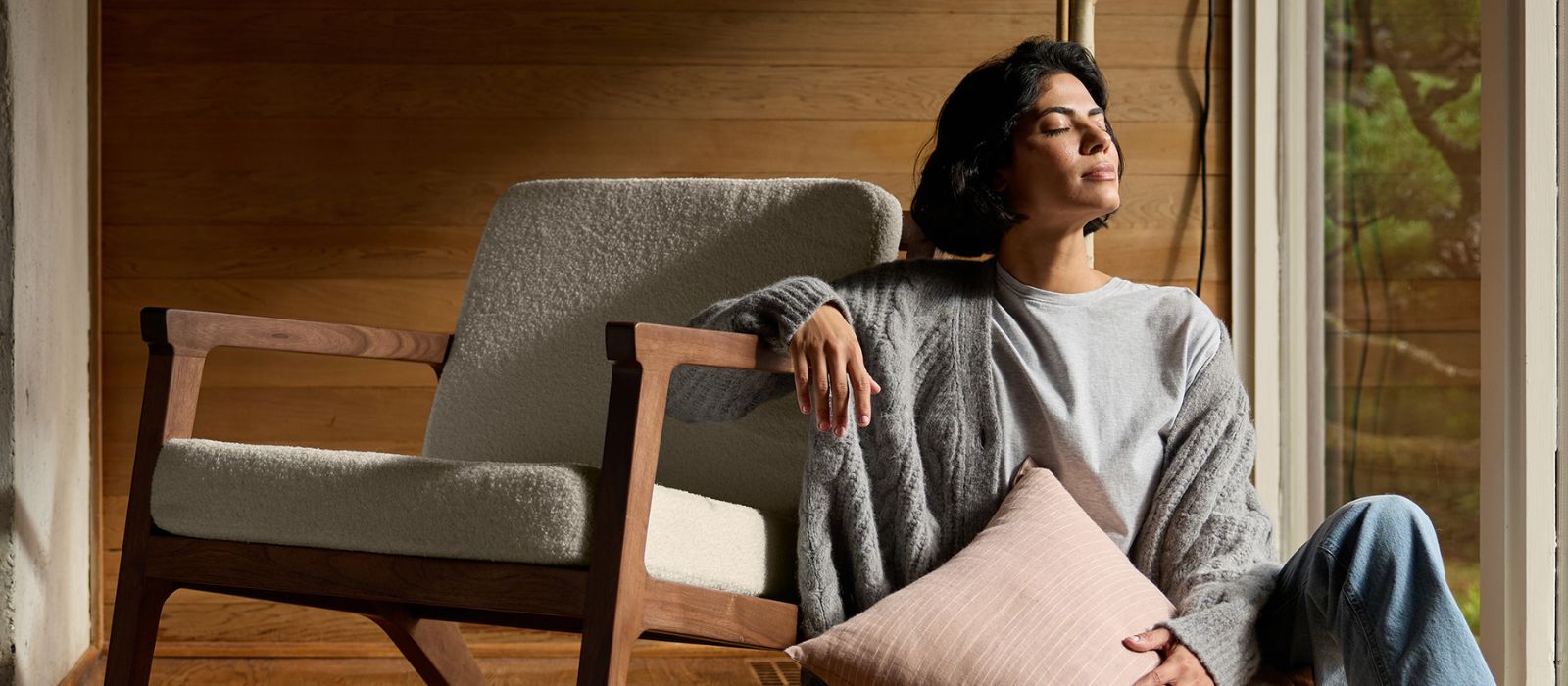 A woman sits next to a Cozy Earth Coronado Lounge Chair holding a decorative pillow