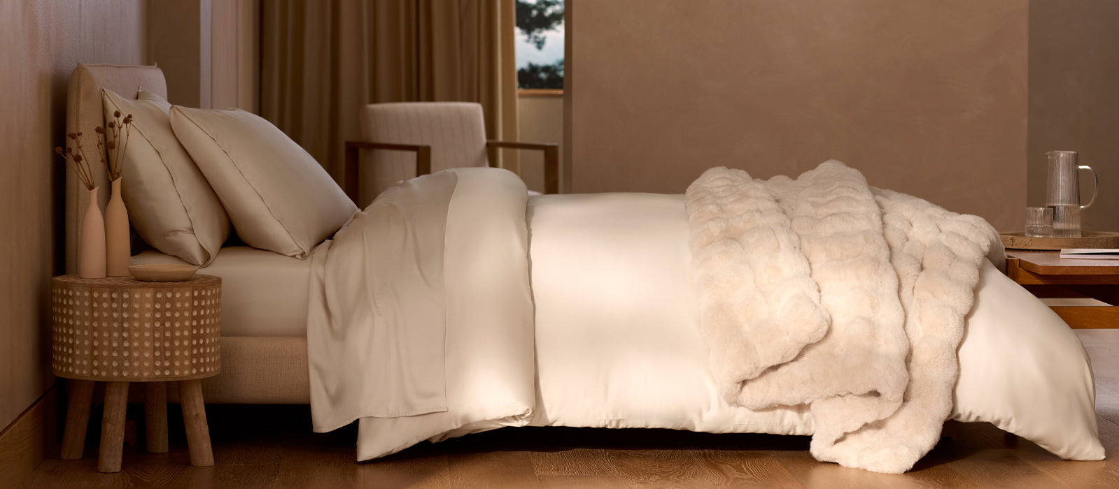 A bed in neutral tones is layered with Cozy Earth bedding