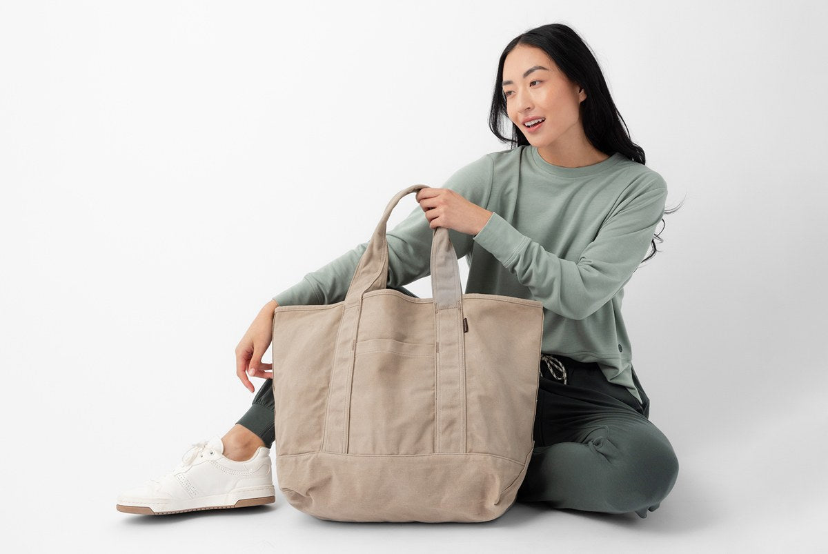 Women sitting down holding a Cozy Earth Tote bag