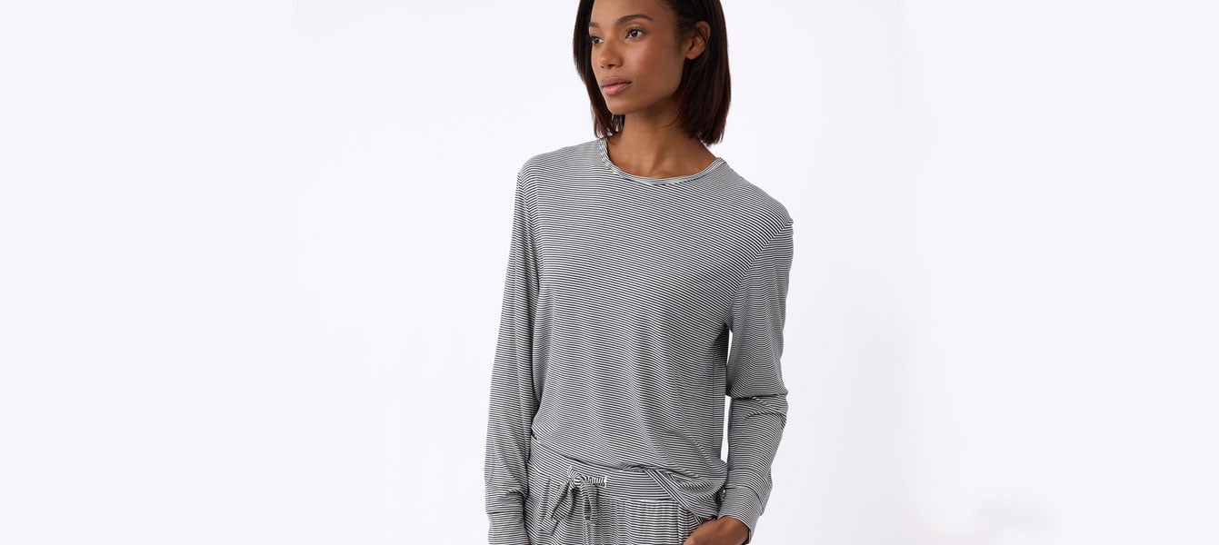 A woman wears Women's Bamboo Stretch Knit Long Sleeve Lounge Tee in Eclipse Mini Stripe