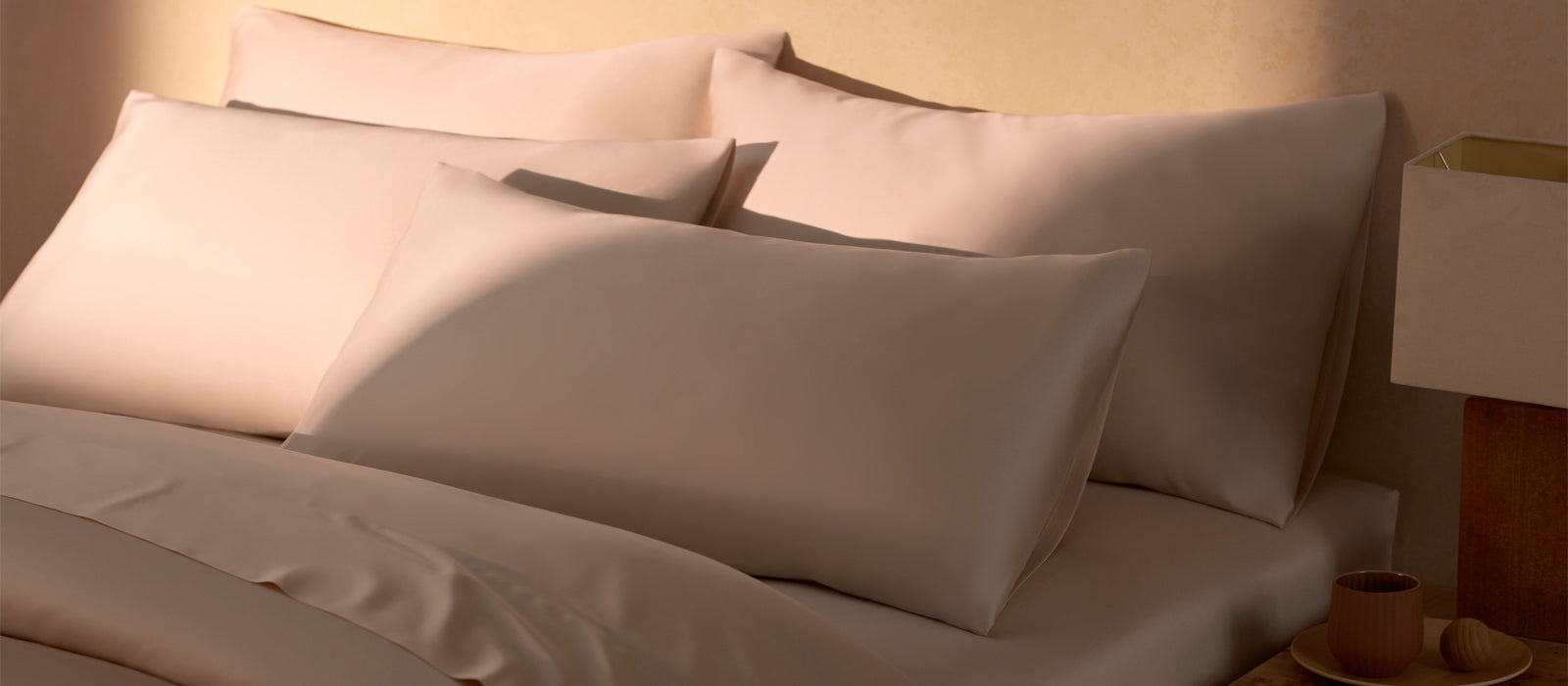 Four pillows in Cozy Earth pillowcases sit on a bed bathed in warm light