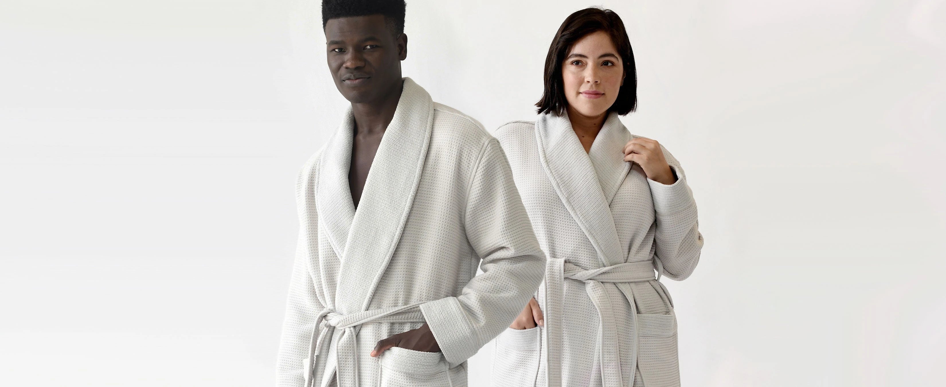 a man and woman model Cozy Earth robes in front of a grey background