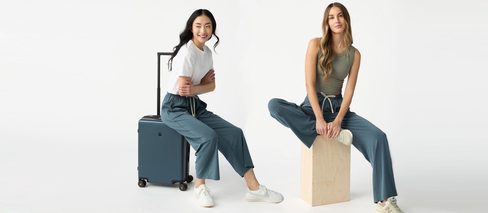 A woman sits on a suitcase wearing Cozy Earth Studio Cropped Wide Leg Pants next to a woman sitting on a box wearing Studio Wide Leg Pants in Dawn