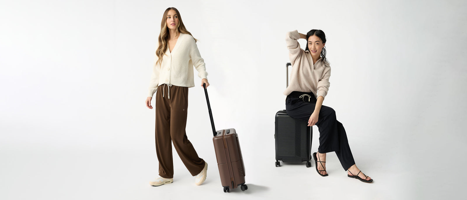 a woman with long blond hair pulls a brown suitcase next to a dark haired woman stis on a black suitcase