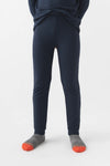 A child wears Cozy Earth Children's Bamboo Waffle Knit Base Layer Pant in navy, paired with gray socks with orange toes, standing against a plain white background. The upper body is mostly out of the frame.|Color:Navy