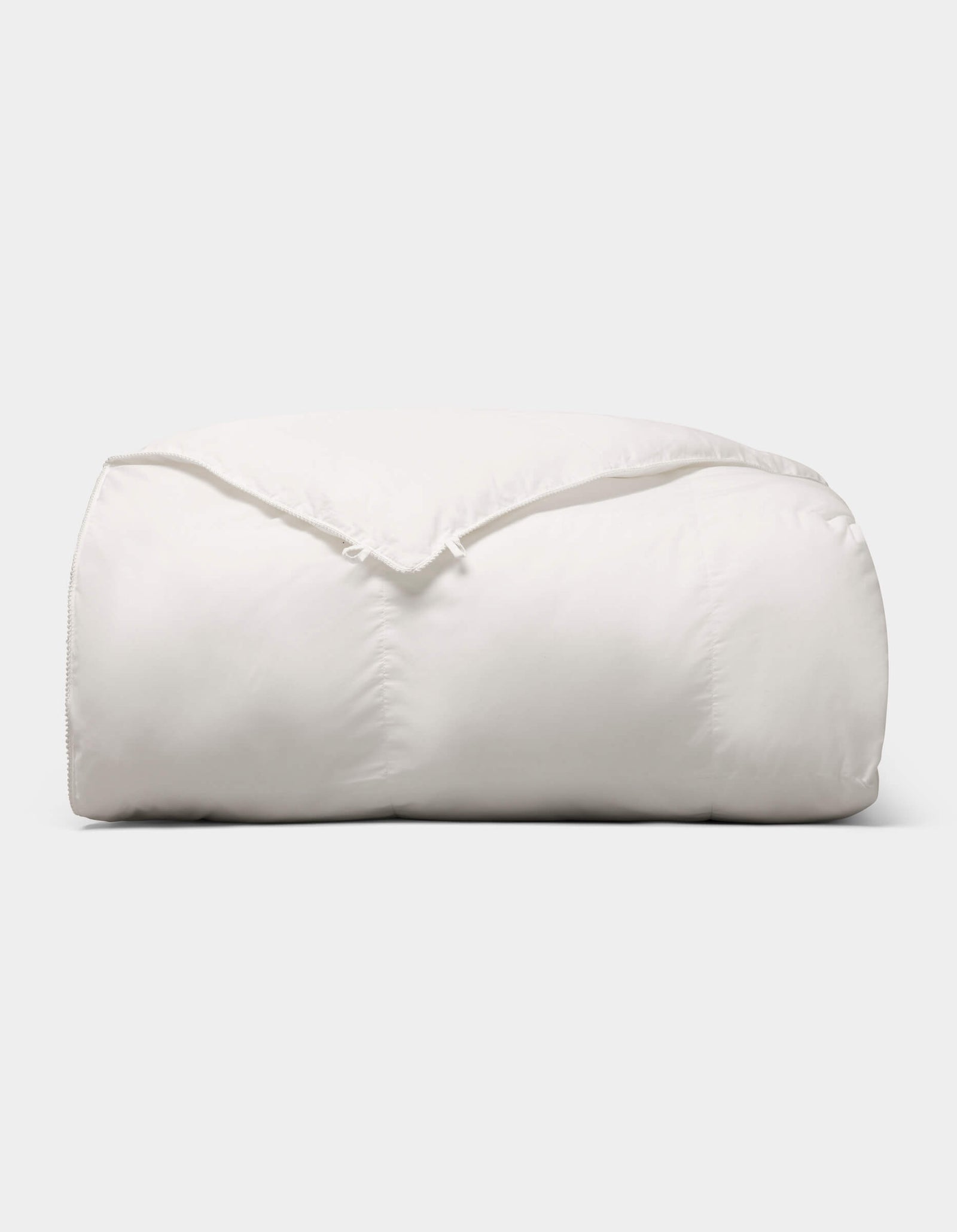 The Cozy Earth Soft-Wash Cotton Bedding Deluxe Bundle - Down Alternative is a fluffy, soft white comforter neatly folded against a plain light background.