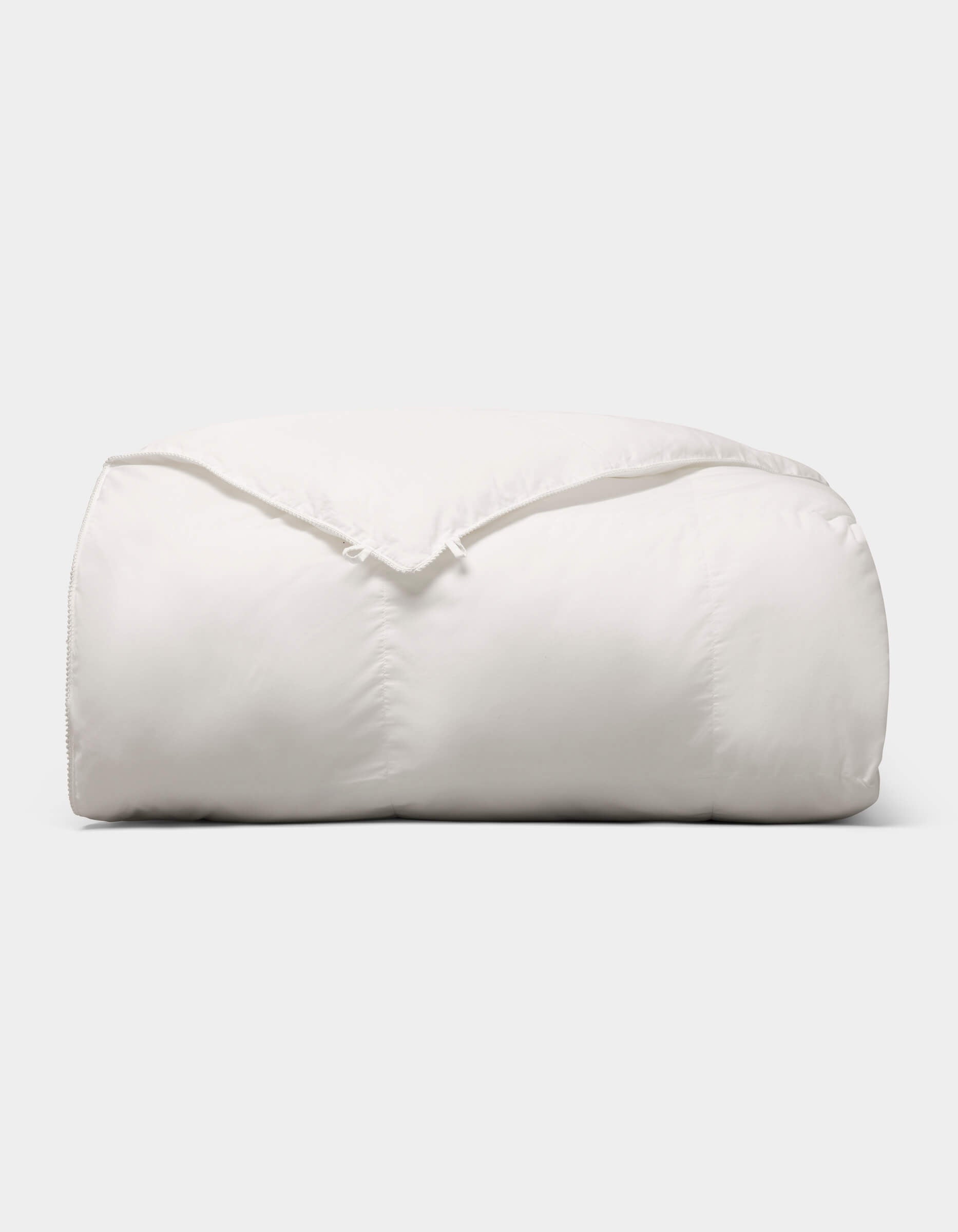 The Cozy Earth Soft-Wash Cotton Bedding Deluxe Bundle - Down Alternative is a fluffy, soft white comforter neatly folded against a plain light background.