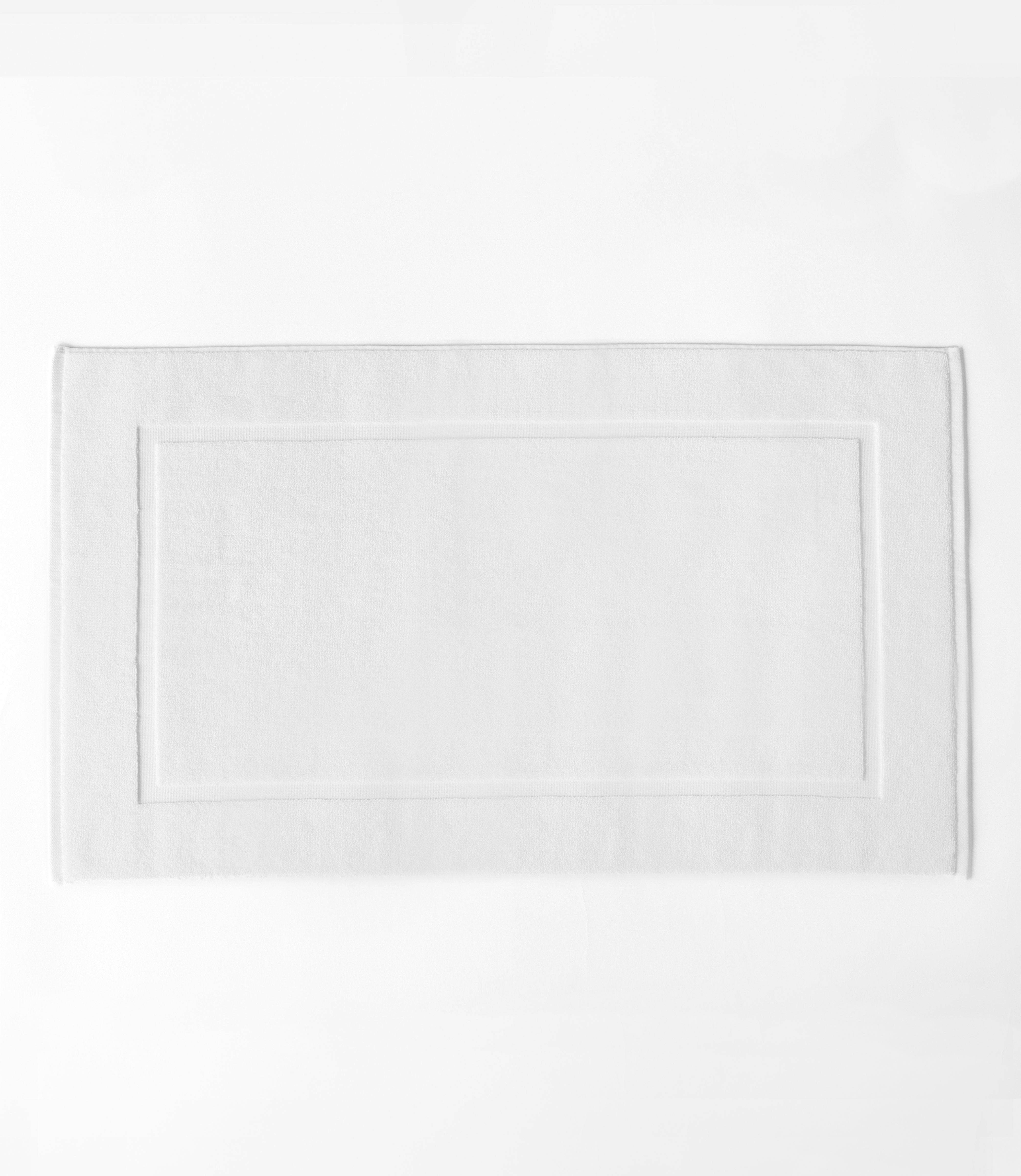 White Premium Plush Bath Mat resting on white background.|Color:White