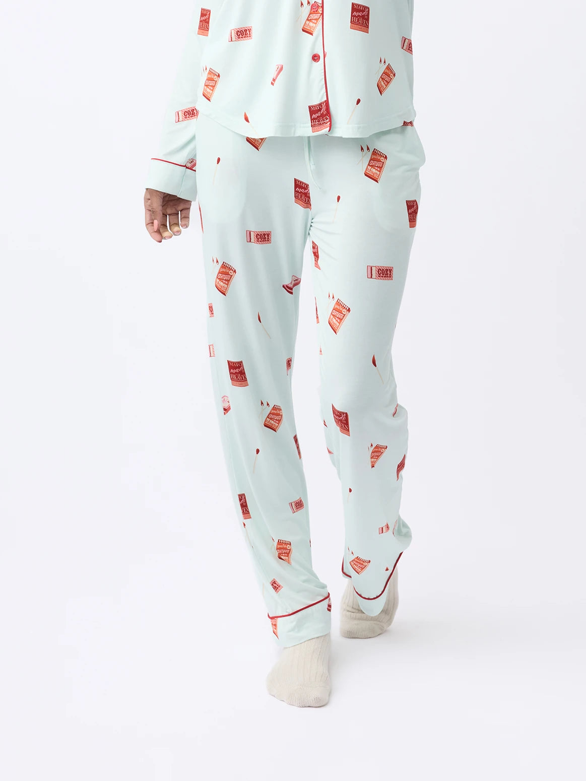 A person wearing Cozy Earth Women's Stretch-Knit Bamboo Pajama Pant in light blue with a red hot sauce bottle print and white socks, poses against a plain, light background. |Color:Perfect Match