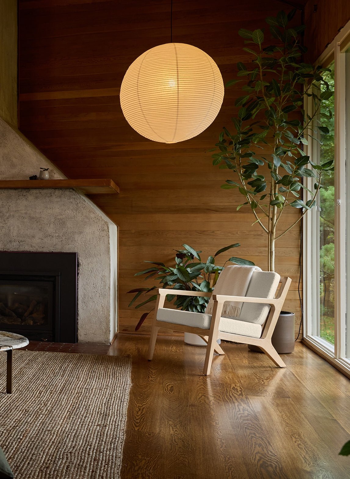 The Cozy Earth Coronado Lounge Chair sits in a room with a concrete fireplace and wood floors and walls.