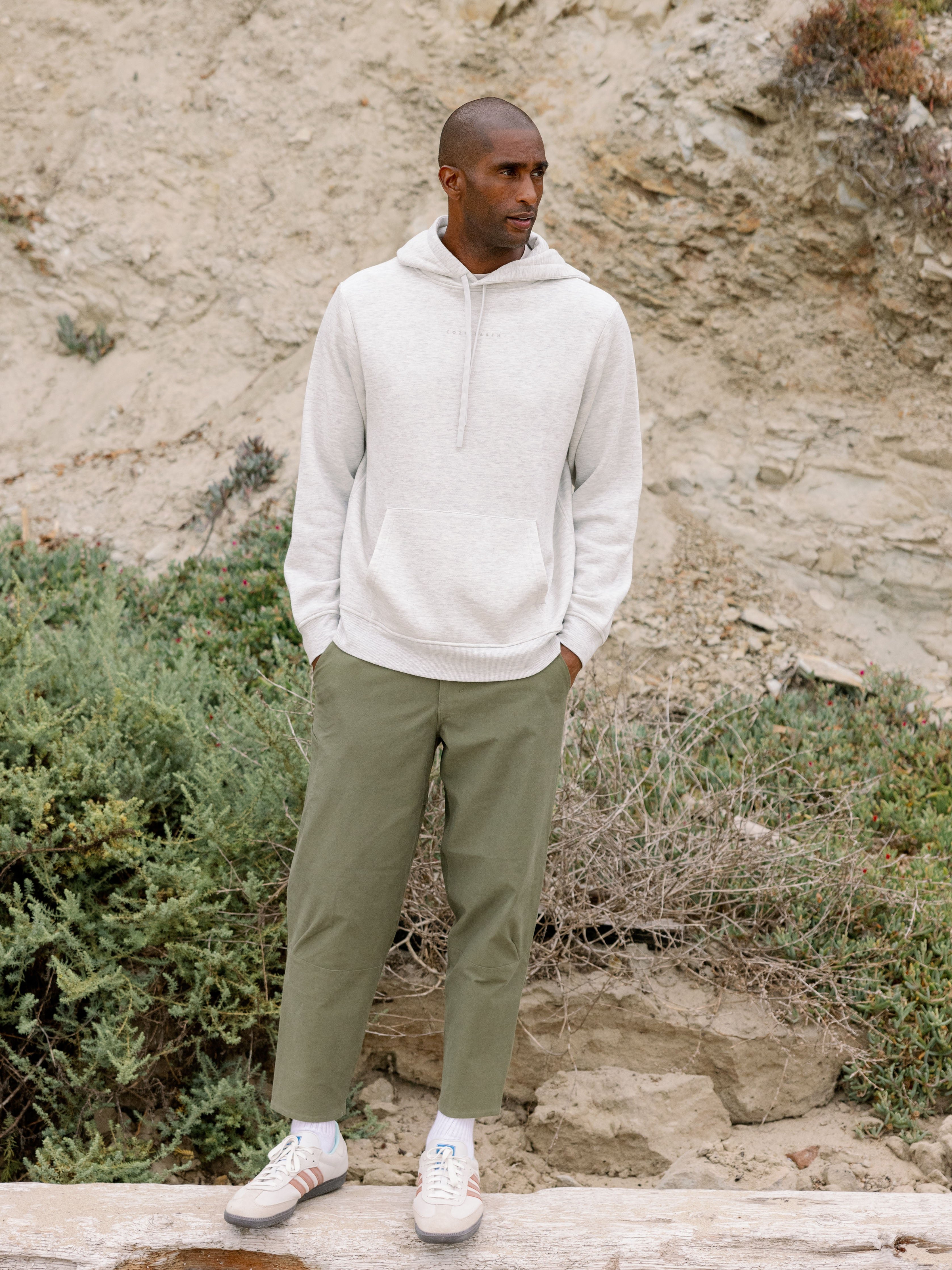 Man wearing heather grey cityscape hoodie with rocky backdrop 