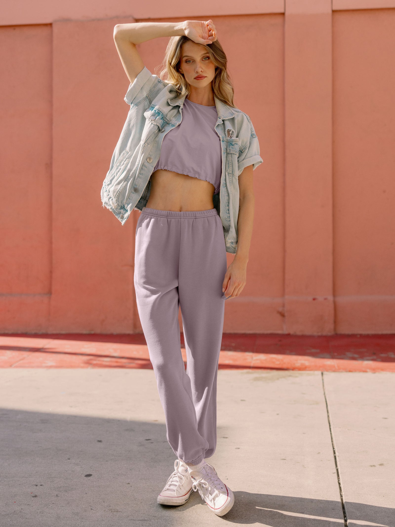 Dusty Orchid CityScape Joggers. The Joggers are being worn by a female model. The photo is taken with the models hand by the pocket of the joggers. The back ground is a downtown area. 