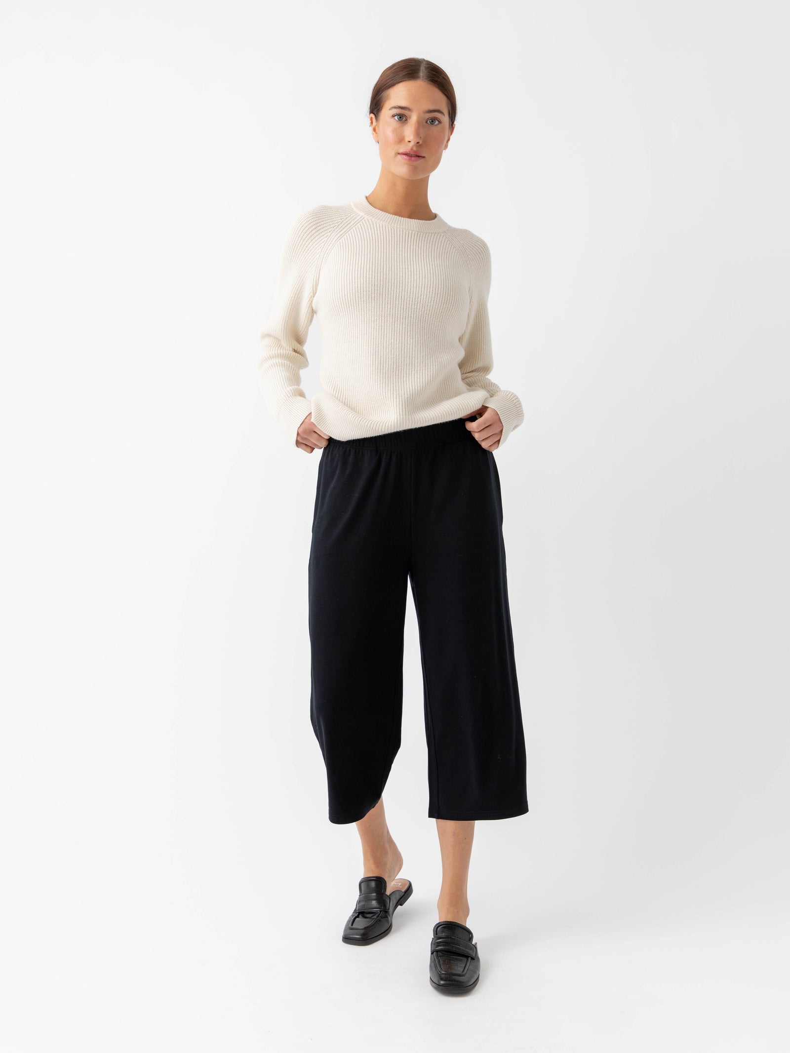 Woman wearing alabaster classic crewneck and black pants with white background 