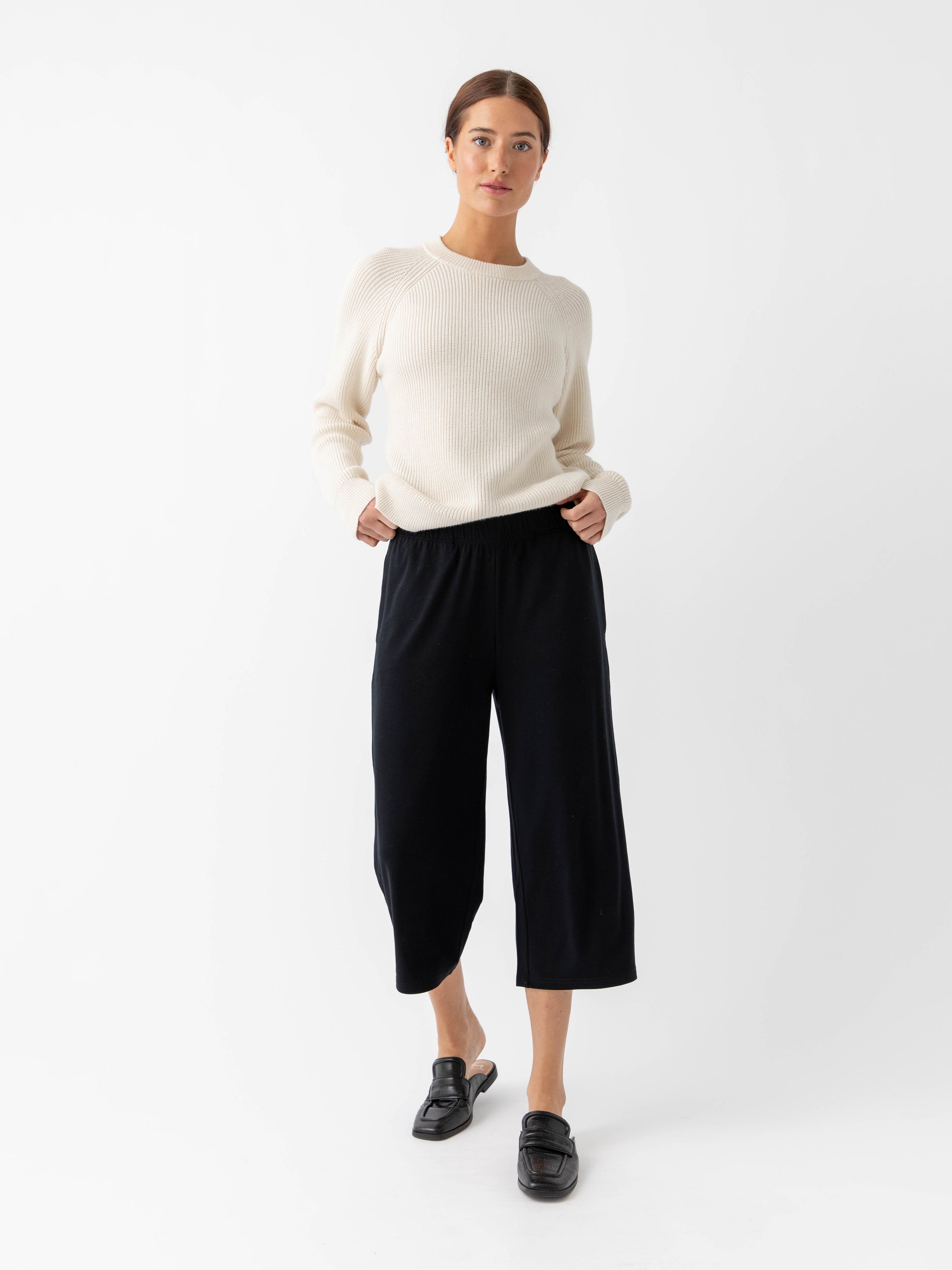 Woman wearing alabaster classic crewneck and black pants with white background |Color:Alabaster