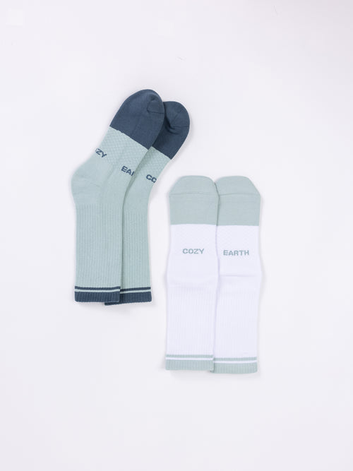 Two pairs of Essential Calf Socks are displayed on a white background. One pair is light green with dark green toes, heels, and cuffs, featuring the word 