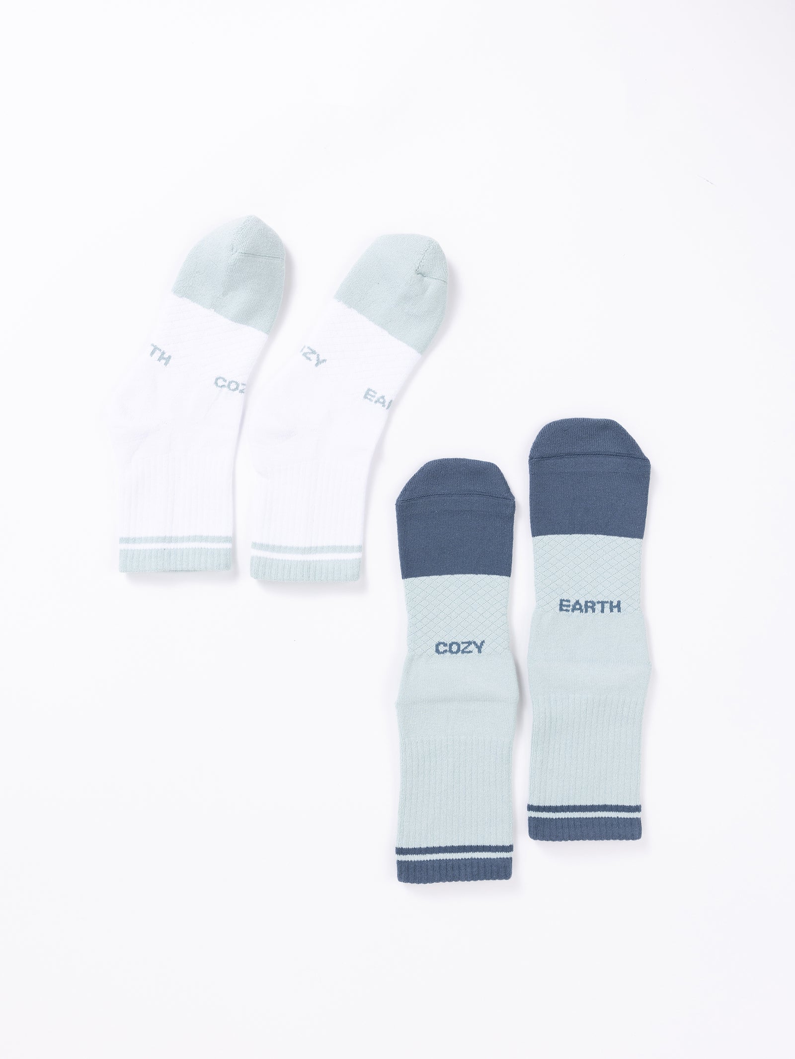 Two pairs of socks from the Essential Quarter Sock 2-Pack by Cozy Earth displayed on a white background. The first pair is white with light green toes and heels, and the words "COZY" and "EARTH" embroidered near the top. The second pair is light green with dark green toes, heels, and cuffs, featuring the same words. 