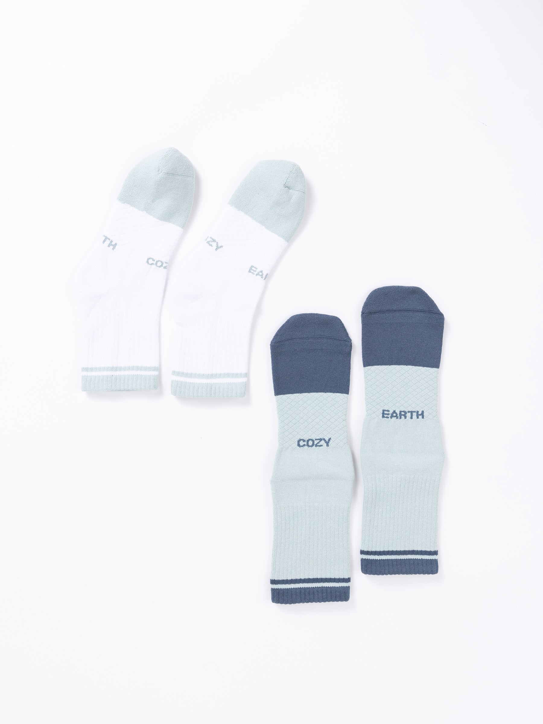 Two pairs of socks from the Essential Quarter Sock 2-Pack by Cozy Earth displayed on a white background. The first pair is white with light green toes and heels, and the words "COZY" and "EARTH" embroidered near the top. The second pair is light green with dark green toes, heels, and cuffs, featuring the same words. |Color:Arctic