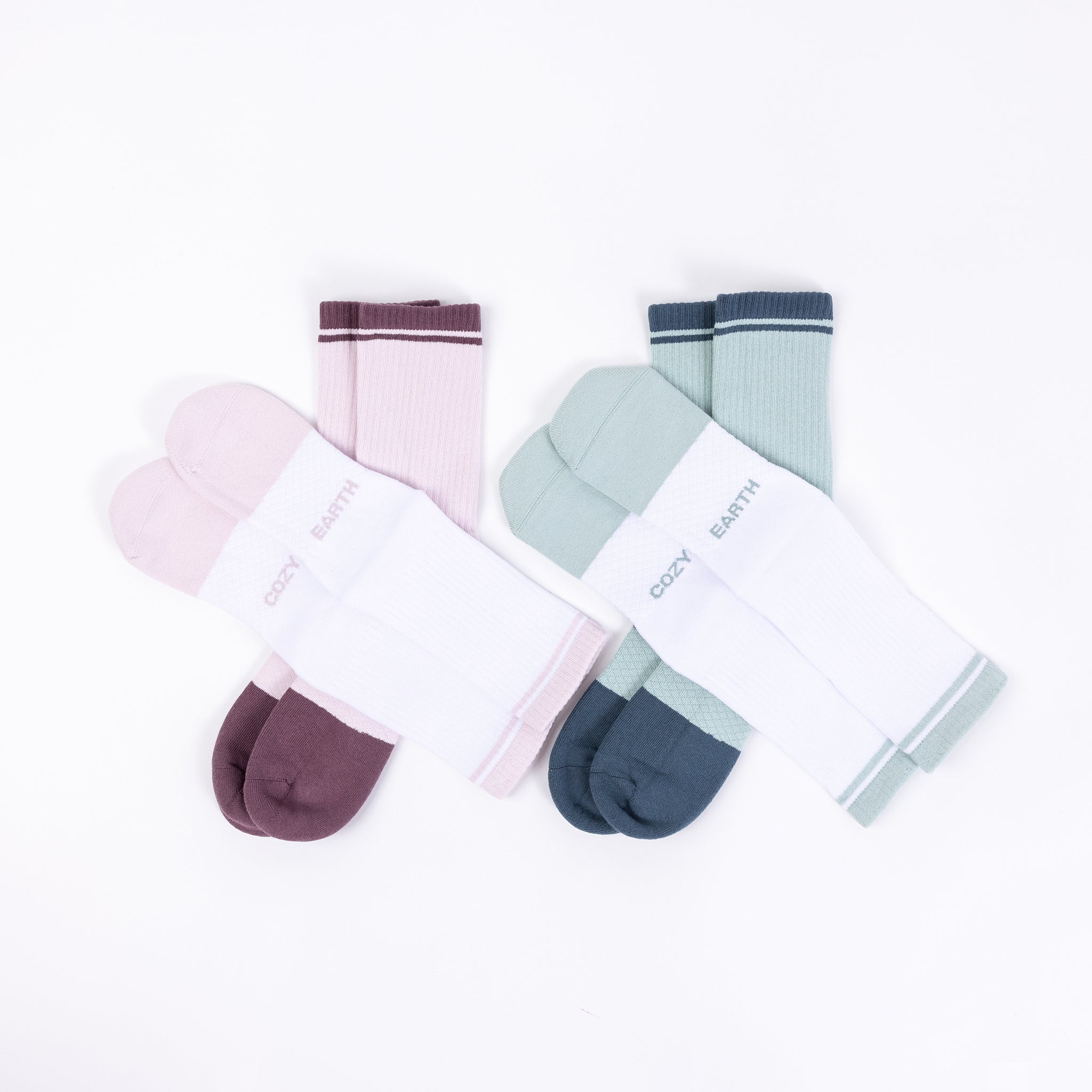 A set of four pairs of Essential Calf Socks from Cozy Earth displayed against a white background. Each pair includes one solid color sock and one white sock with a matching colored stripe at the top. The colors featured are pink, green, dark teal, and an additional vibrant hue. The brand name "COZY EARTH" is clearly visible on each sock. |Color:Arctic/Lilac