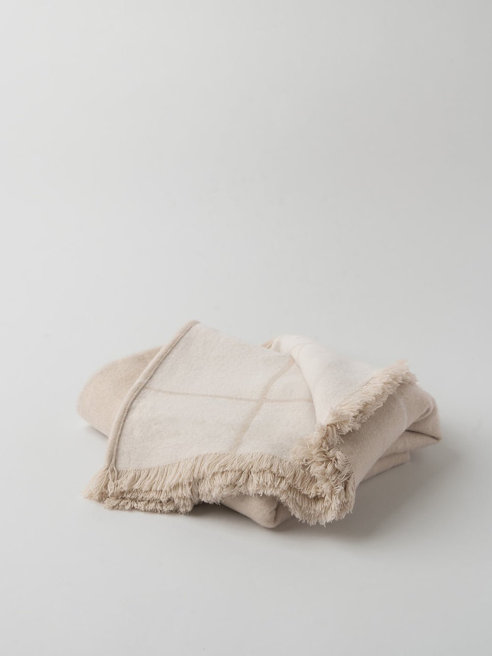 Beige windowpane blanket half folded showing tasseled edge |Color:Beige/Creme