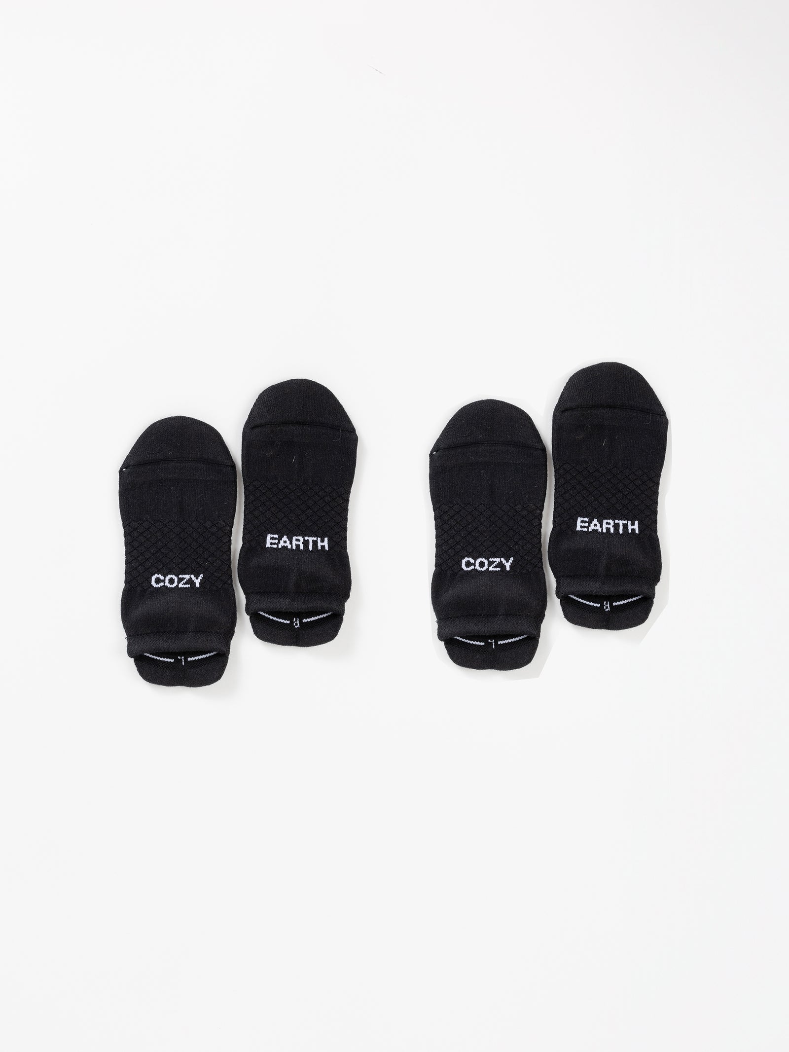 The Essential Ankle Sock 2-Pack from Cozy Earth is displayed on a white background. The black ankle socks feature the words "COZY" and "EARTH" printed in white near the toes, with "COZY" appearing on one sock and "EARTH" on the other. 