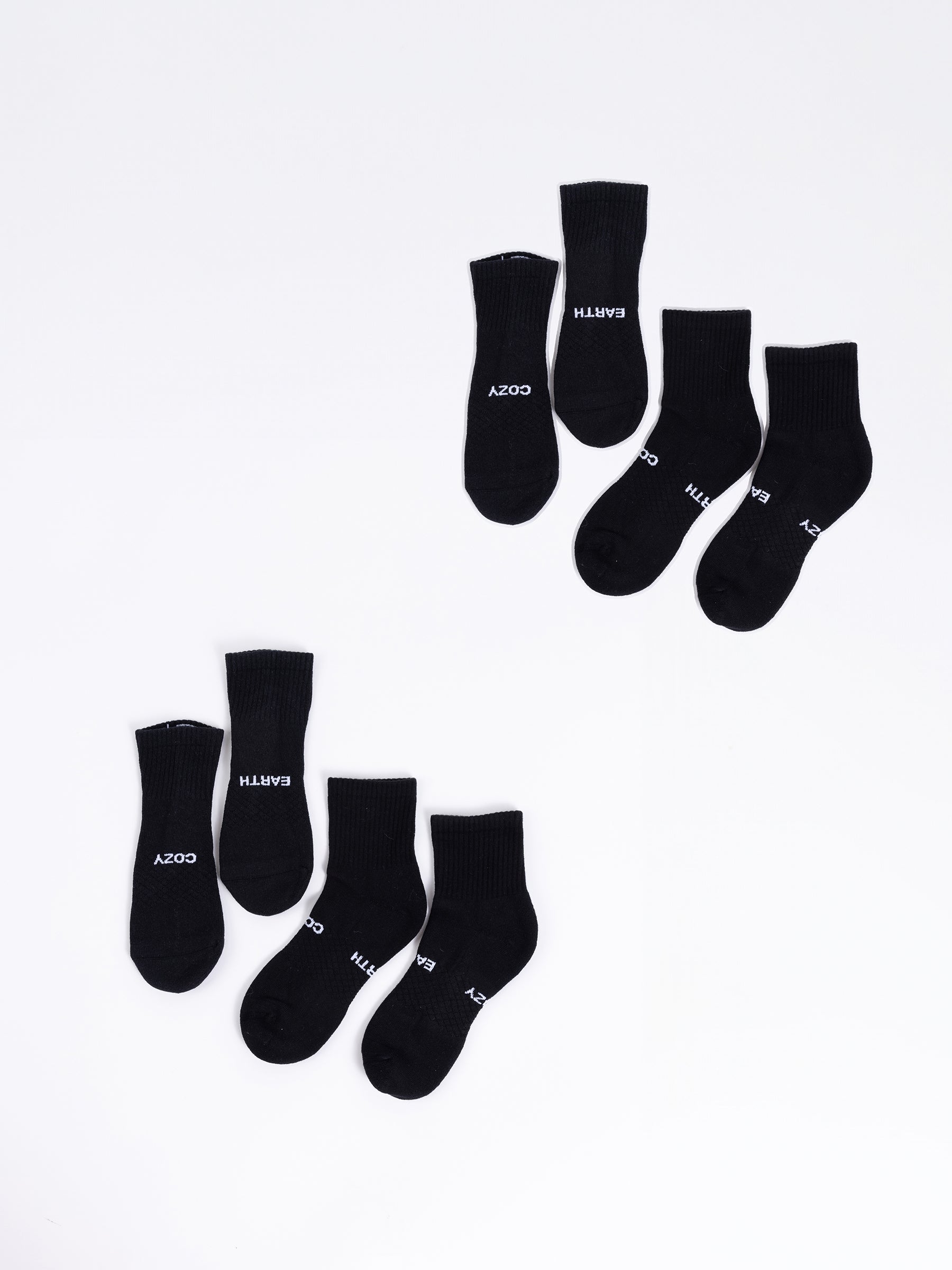 A four-pack of black quarter socks from Cozy Earth, each pair arranged unevenly against a white background. Each sock features the words "COZY EARTH" printed in white near the toes. |Color:Black