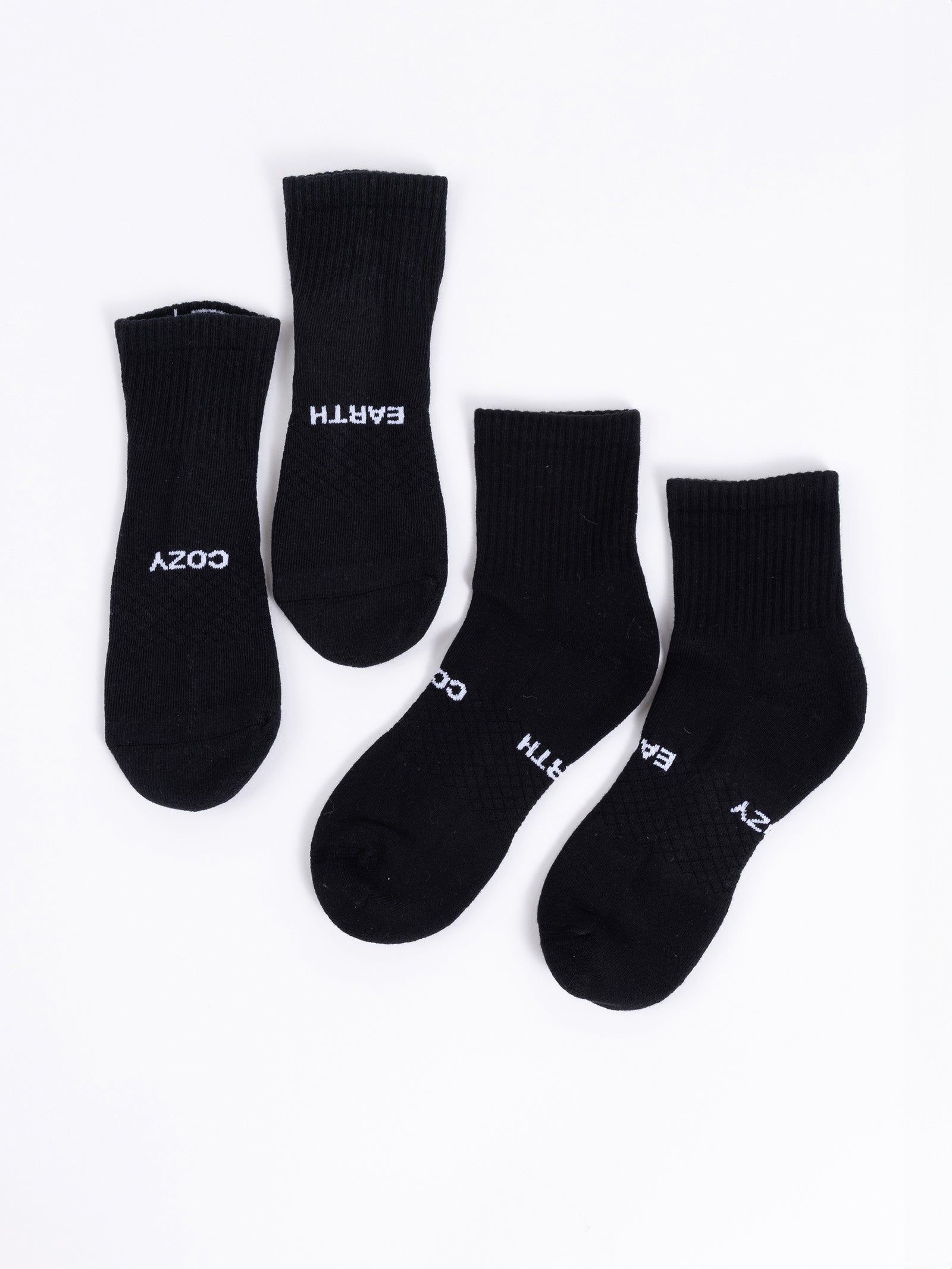 Four black socks from the Cozy Earth Essential Quarter Sock 2-Pack are displayed on a white background. Two of the socks feature the word "COZY," while the other two are labeled with "EARTH." Each pair is placed side by side. 