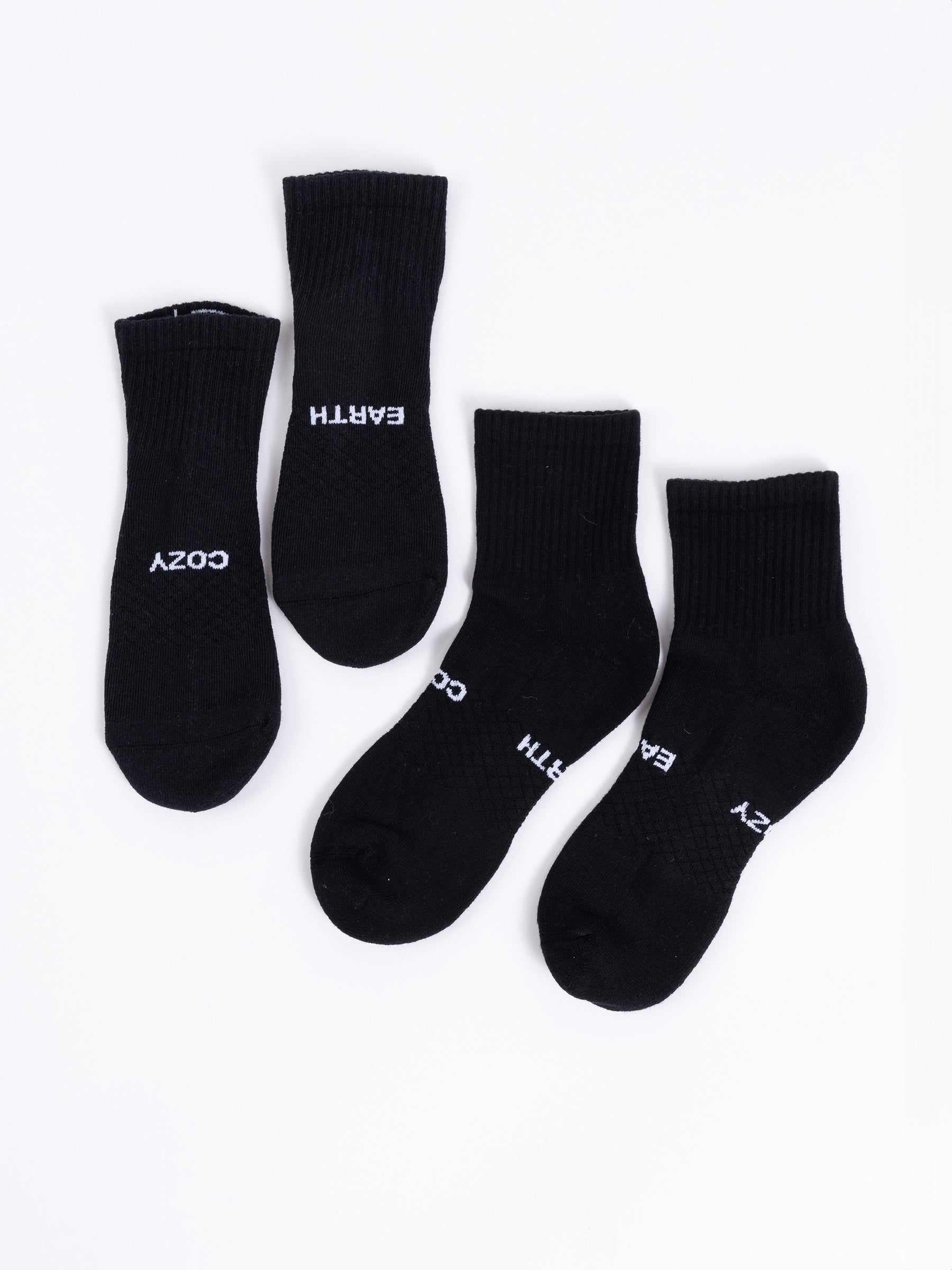 Four black socks from the Cozy Earth Essential Quarter Sock 2-Pack are displayed on a white background. Two of the socks feature the word "COZY," while the other two are labeled with "EARTH." Each pair is placed side by side. |Color:Black