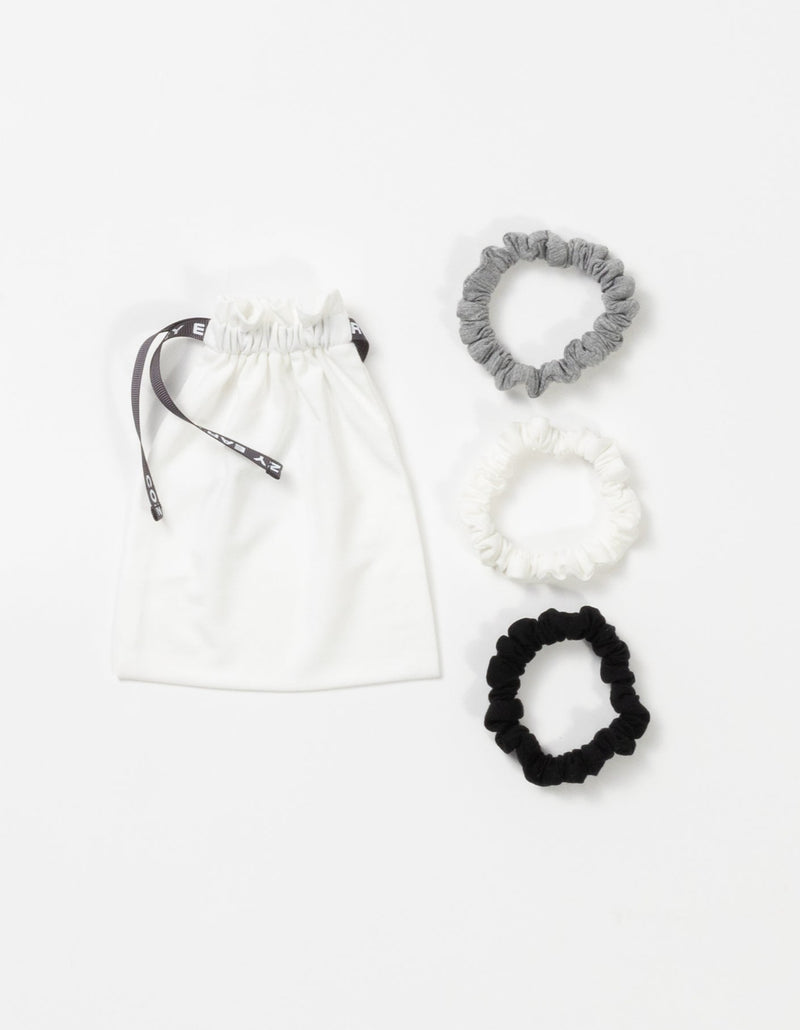 Cozy Earth Bamboo Stretch Knit Skinny Scrunchies in Grey, Ivory, and Black pictured with storage bag on a white background.