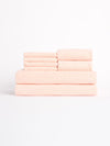 A neatly stacked Luxe Bath Towel Set by Cozy Earth, featuring soft, pale pink towels in various sizes, is arranged against a plain white background. |Color:Blossom