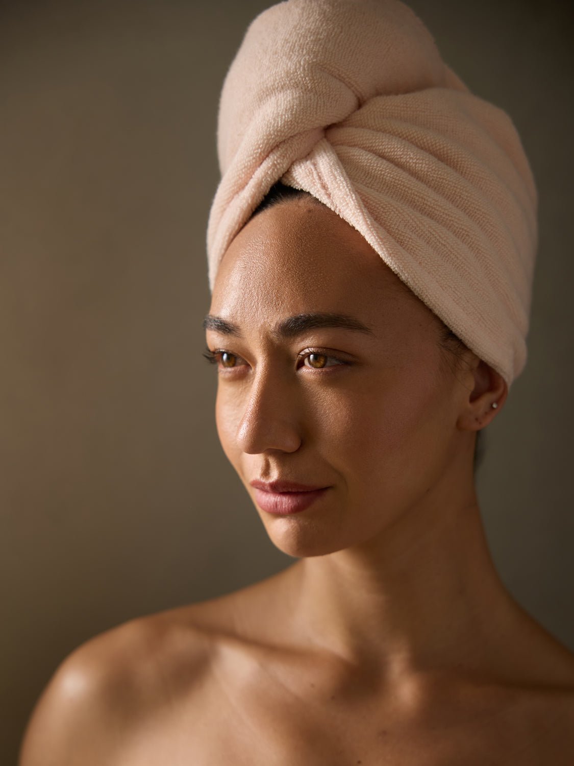 A woman from the shoulders up is wearing a Cozy Earth Luxe Hair Towel in Blossom. 