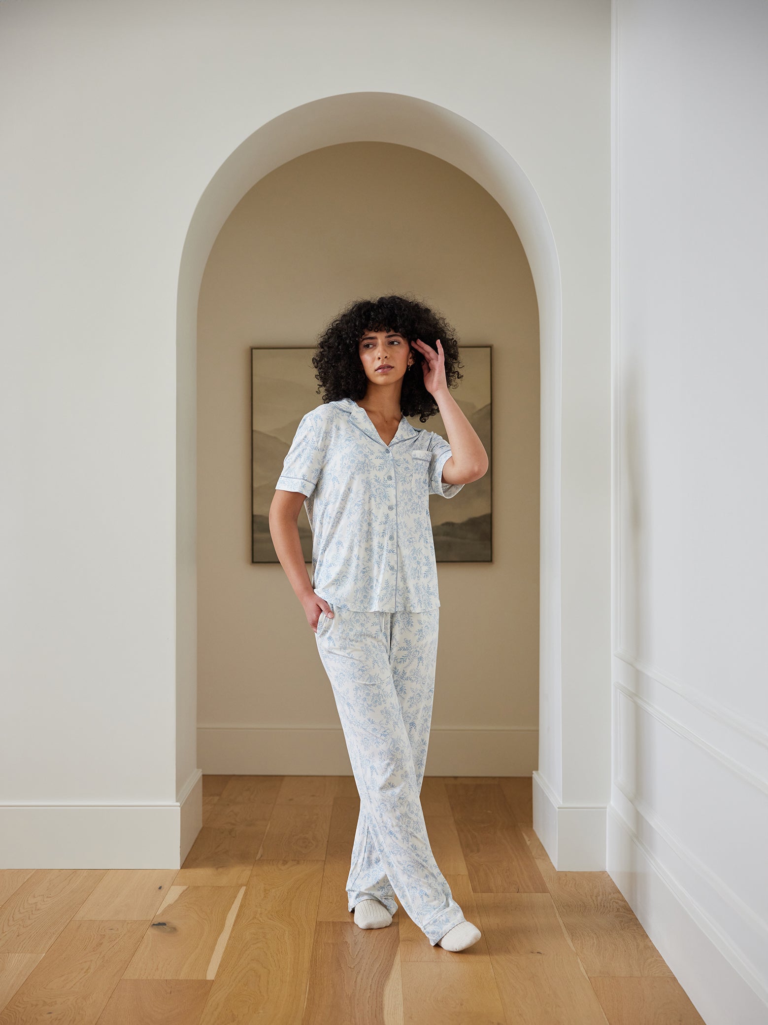 Woman standing in hallway in blue toile pajama set 