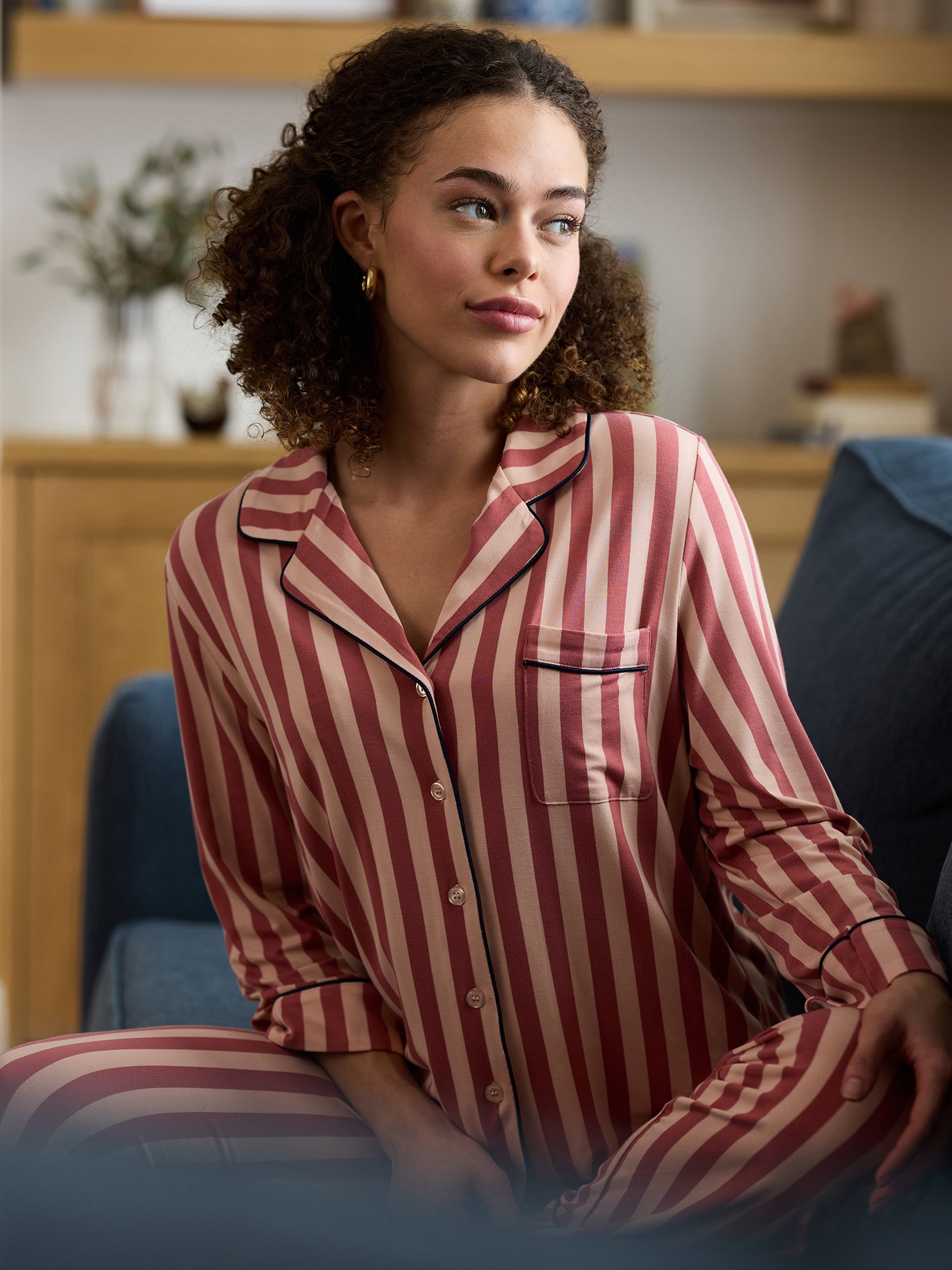 Woman in living room wearing long sleeve blush stripe pajama top 