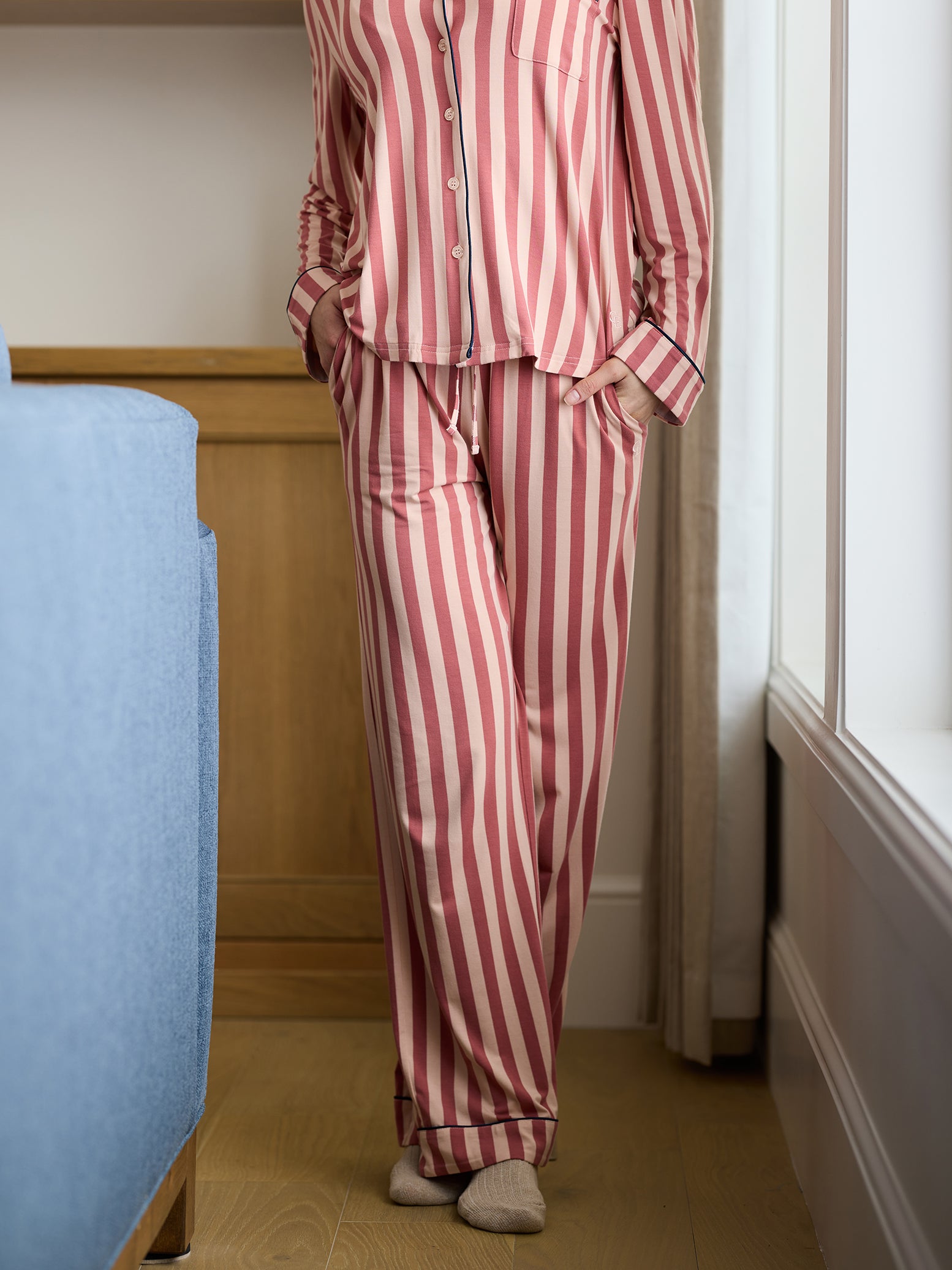 Woman wearing blush stripe pajama pants in living room 