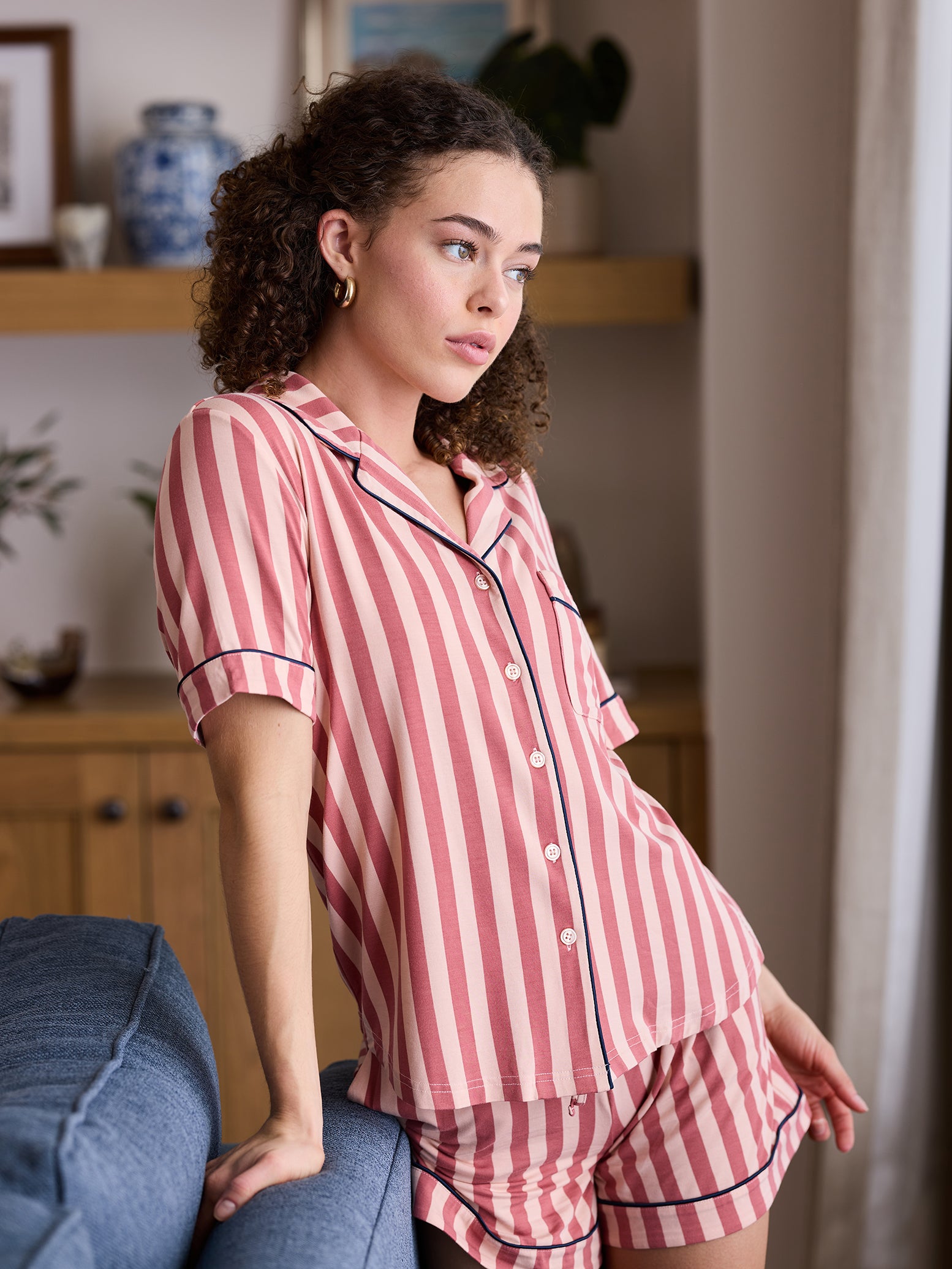 Woman in living room wearing blush stripe short sleeve pajama set 