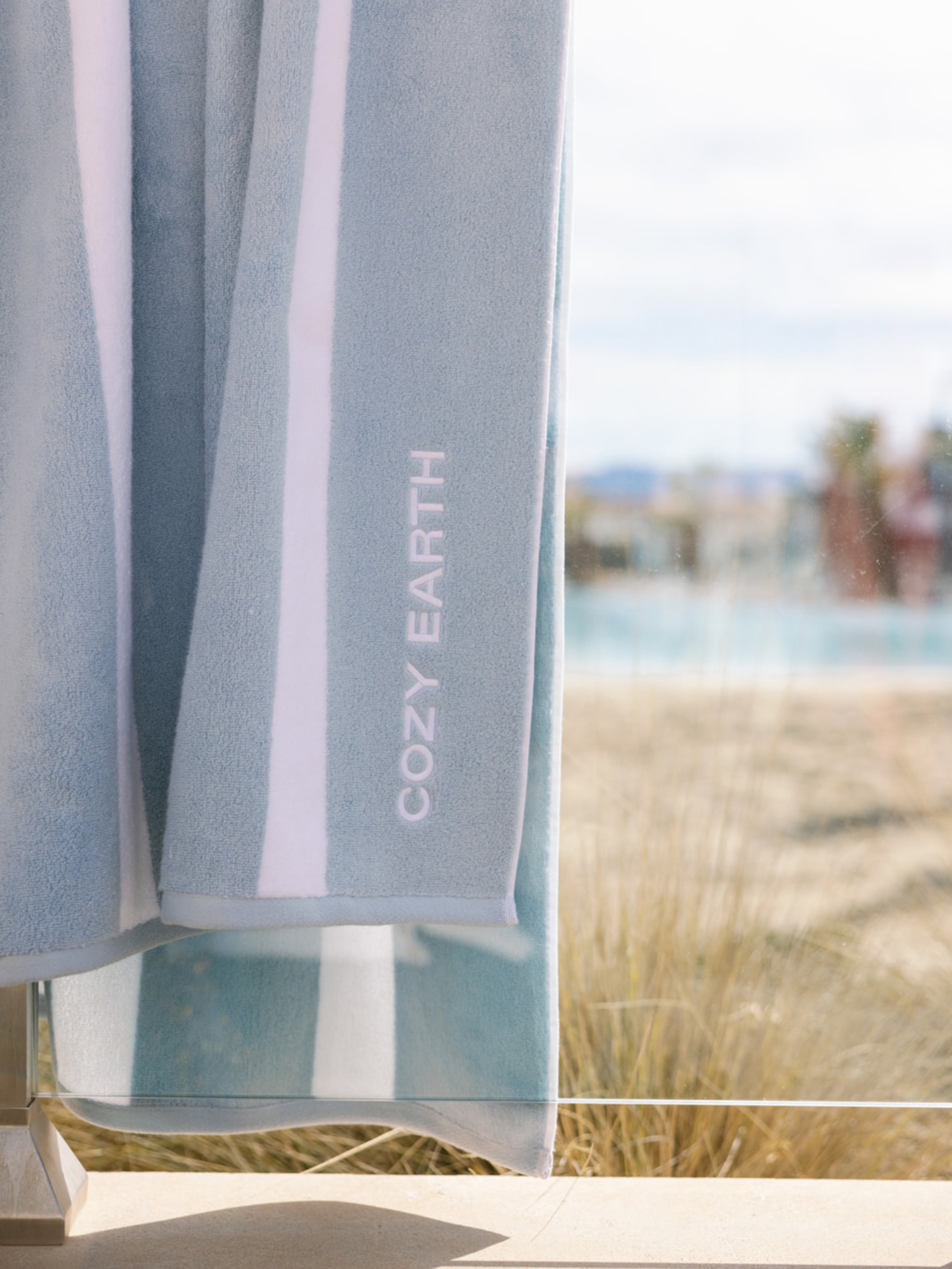 Breeze resort towel draped over glass outside |Color:Breeze