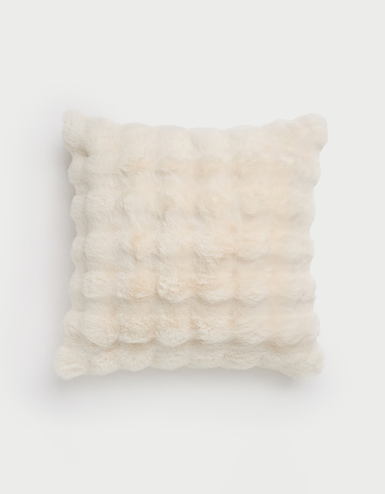 The cozy Bubble Cuddle Pillow by Cozy Earth, a cream-colored faux fur square with a textured grid pattern, is set against a plain white background. |Color:Creme