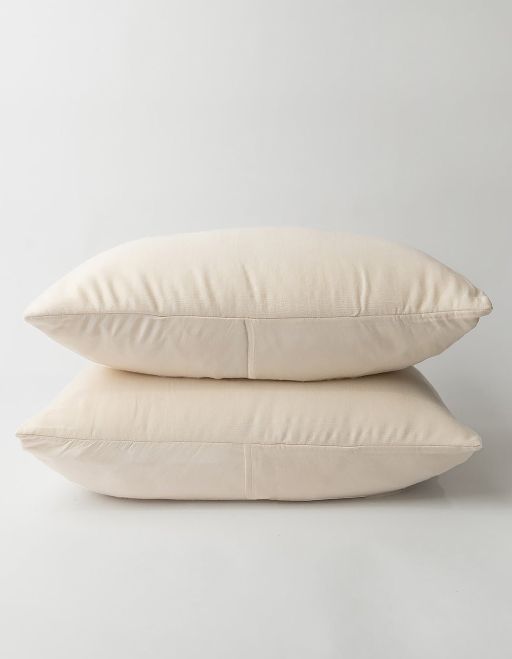Two Aire Bamboo Shams by Cozy Earth, in a soft cream color, are stacked on a white background, highlighting their smooth fabric and minimalist design.|Color:Buttermilk|Size:Standard