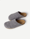 The Lakehouse Clog by Cozy Earth features a minimalist design with grey woolen uppers and natural brown soles. It has a closed toe, open back, and is ideal for indoor wear. A logo is visible on the insole, all showcased on a white background. |Color:Charcoal