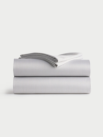 A neatly folded stack of Bamboo Sheet Sets from Cozy Earth, featuring a subtle black and white striped pattern. The sheets are arranged in a minimalist style on a plain white background. |Color:Charcoal Pinstripe