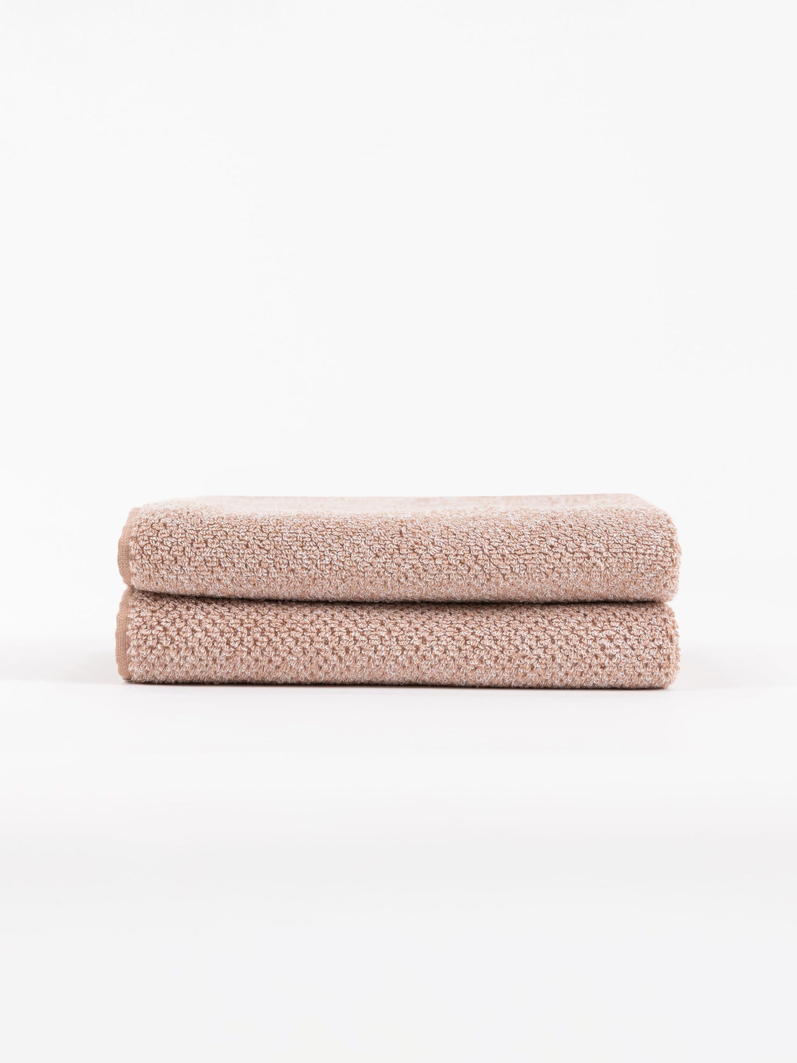 A pair of Nantucket Hand Towels in Heathered Clay is stacked in front of a white background. 