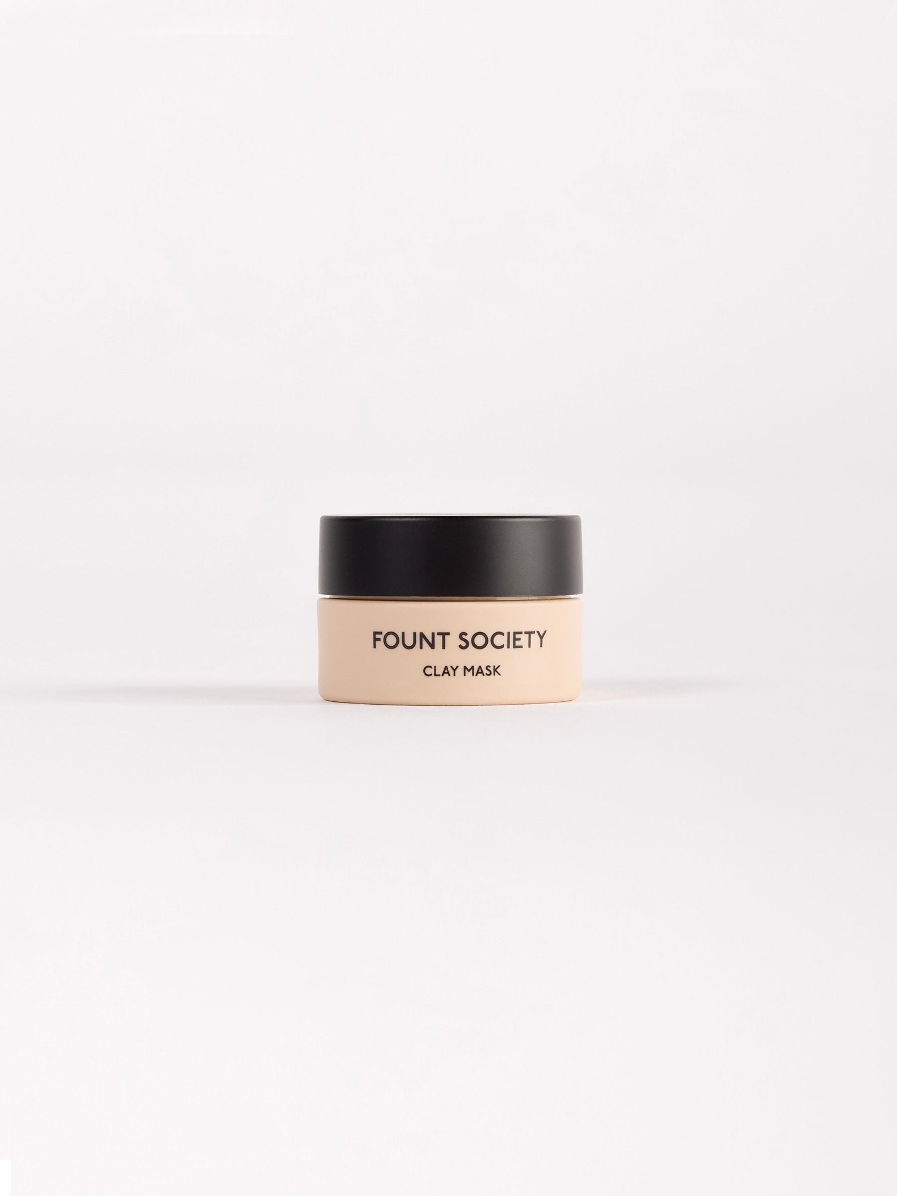 A minimalist product photo of Cozy Earth Clay Mask 10 ML, showcased in a small beige container with a black lid, centered against a plain white background. 