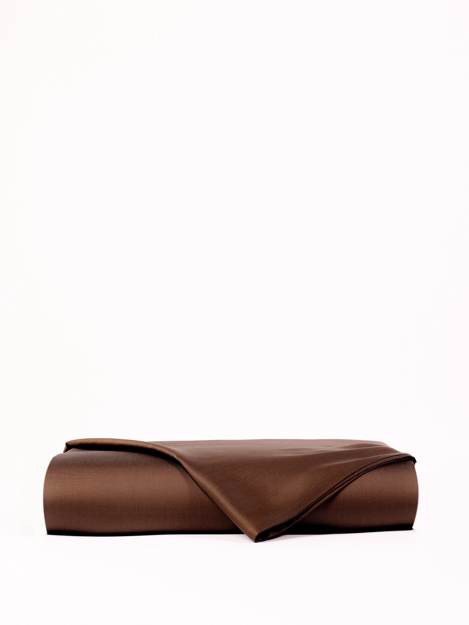 A neatly folded Bamboo Flat Sheet by Cozy Earth is centered against a plain white background. One corner is slightly turned over, revealing the texture and thickness of the sheet fabric. |Color:Coffee