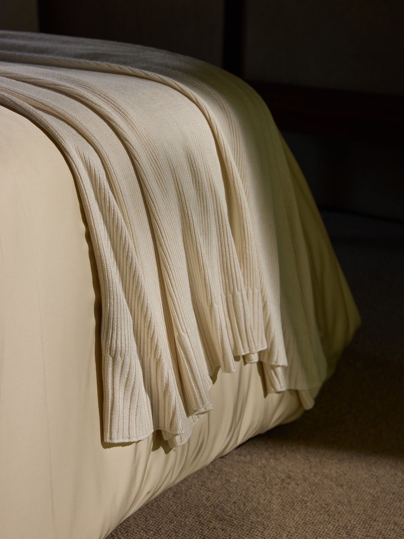 Creme Classic Knit Blanket draped over a bed in the sunlight. |Color:Creme