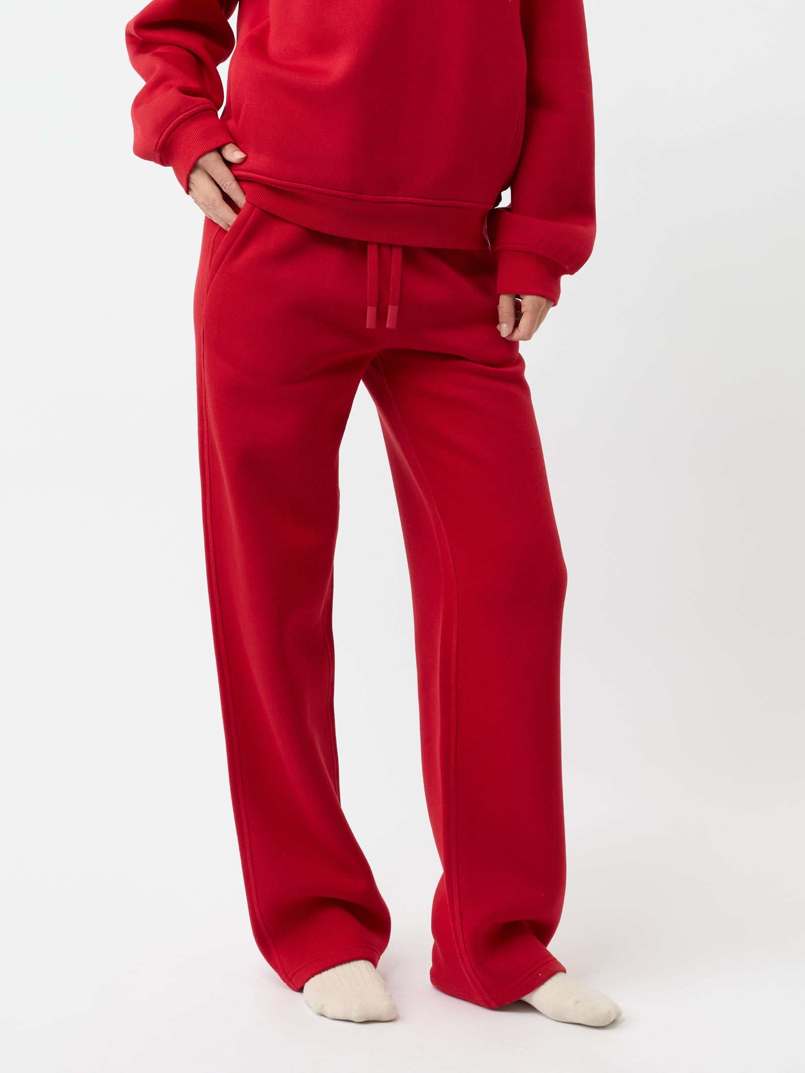 A person wearing a red tracksuit with the long-sleeved top and relaxed-fit Women's CityScape Wide Leg Pant by Cozy Earth, paired with cream socks. The background is plain white. 