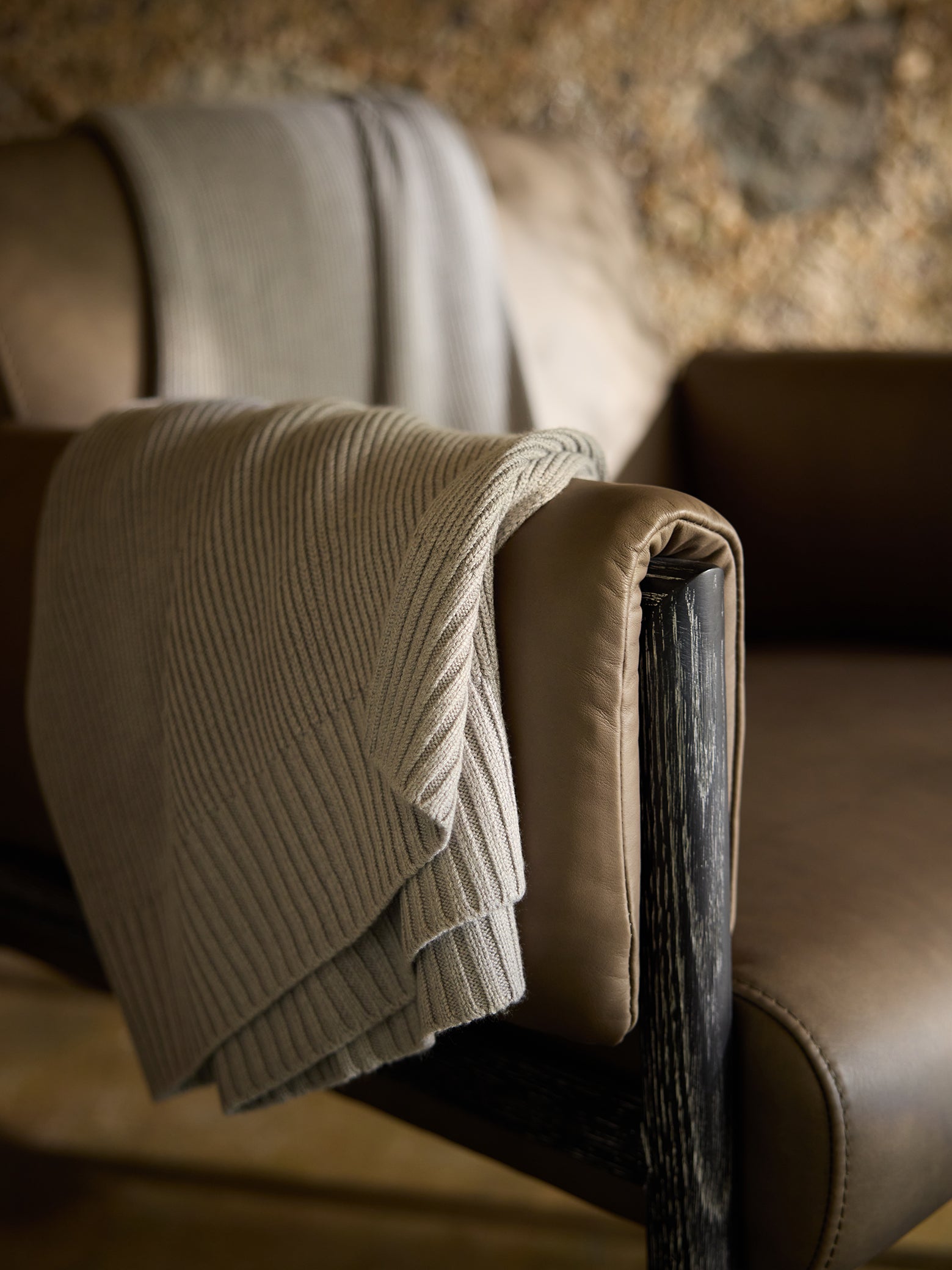 Dove Grey Classic Knit Blanket draped over a leather chair. 