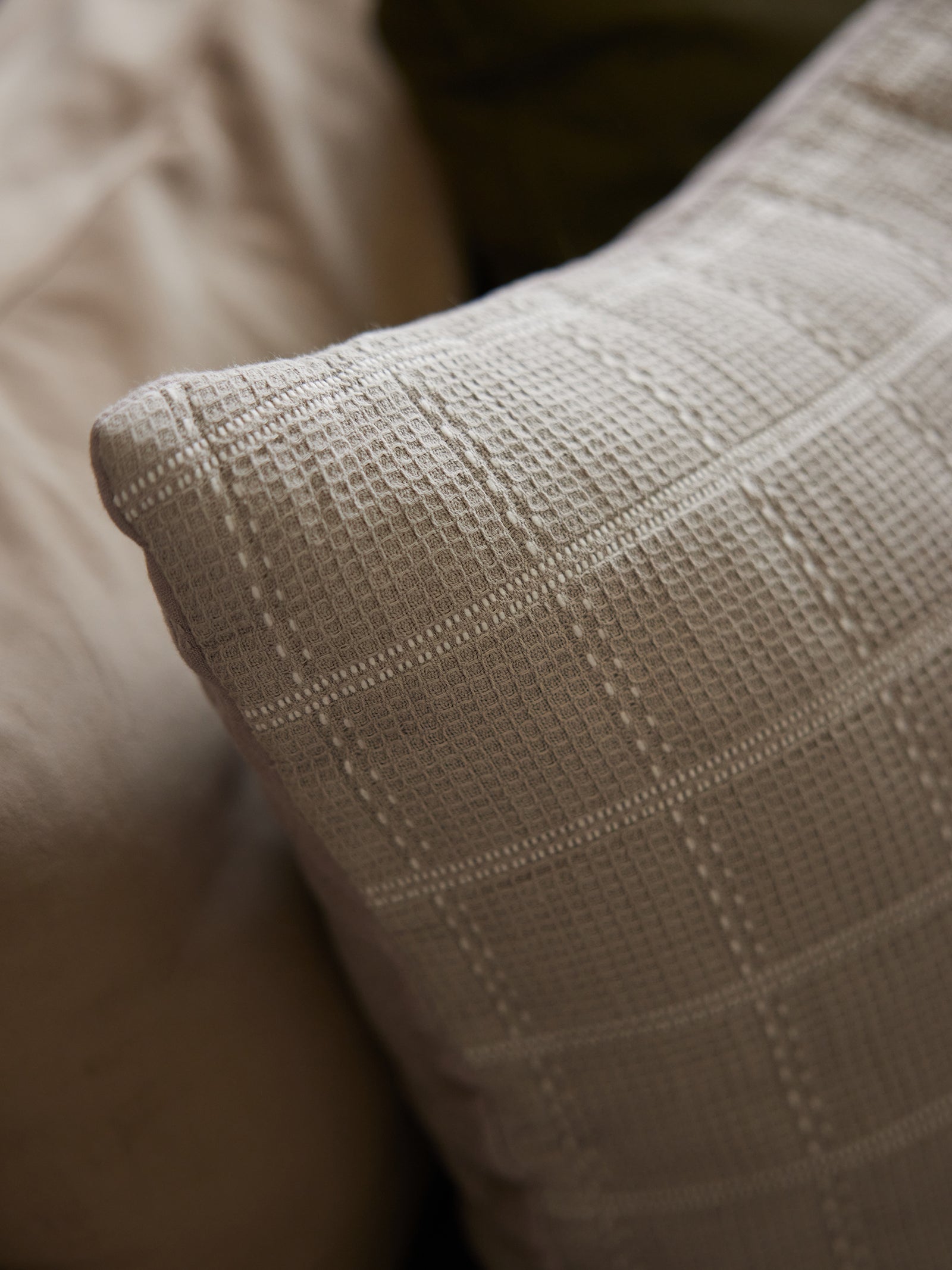 Corner of a dove grey waffle windowpane pillow from Cozy Earth 